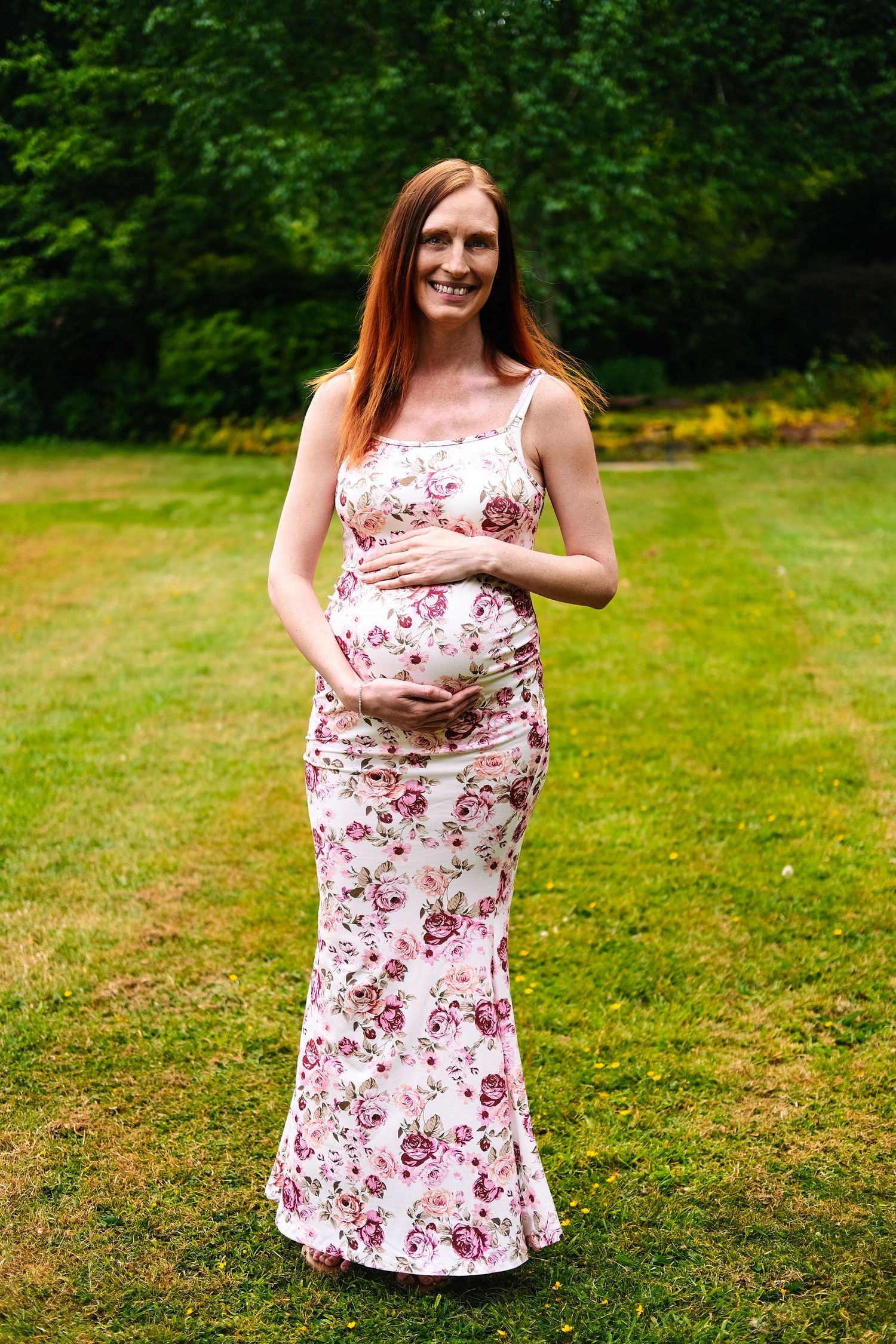 A series of maternity poses showcasing a white and pink floral dress in a garden setting.