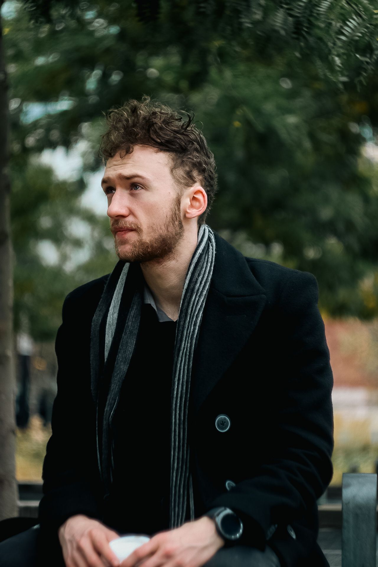 Artistic black and white portraits showing someone in a dark coat outdoors with natural lighting.