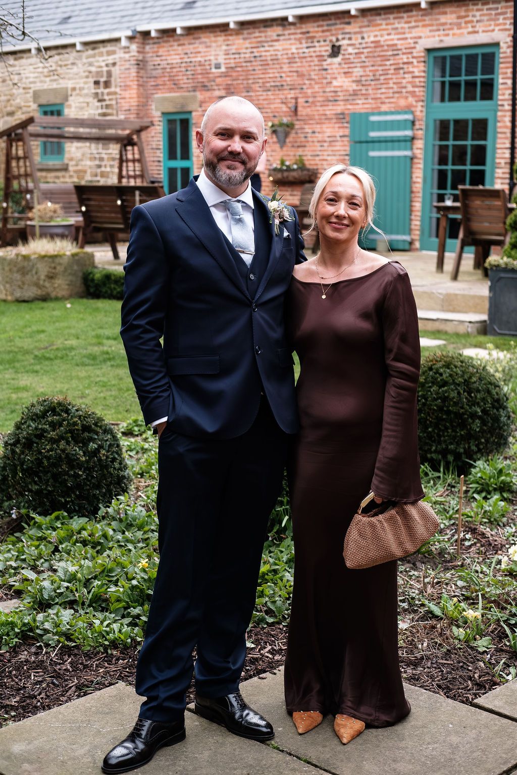 Wedding guests in the walled garden of Dunston Hall's main hall, red brick building behind them