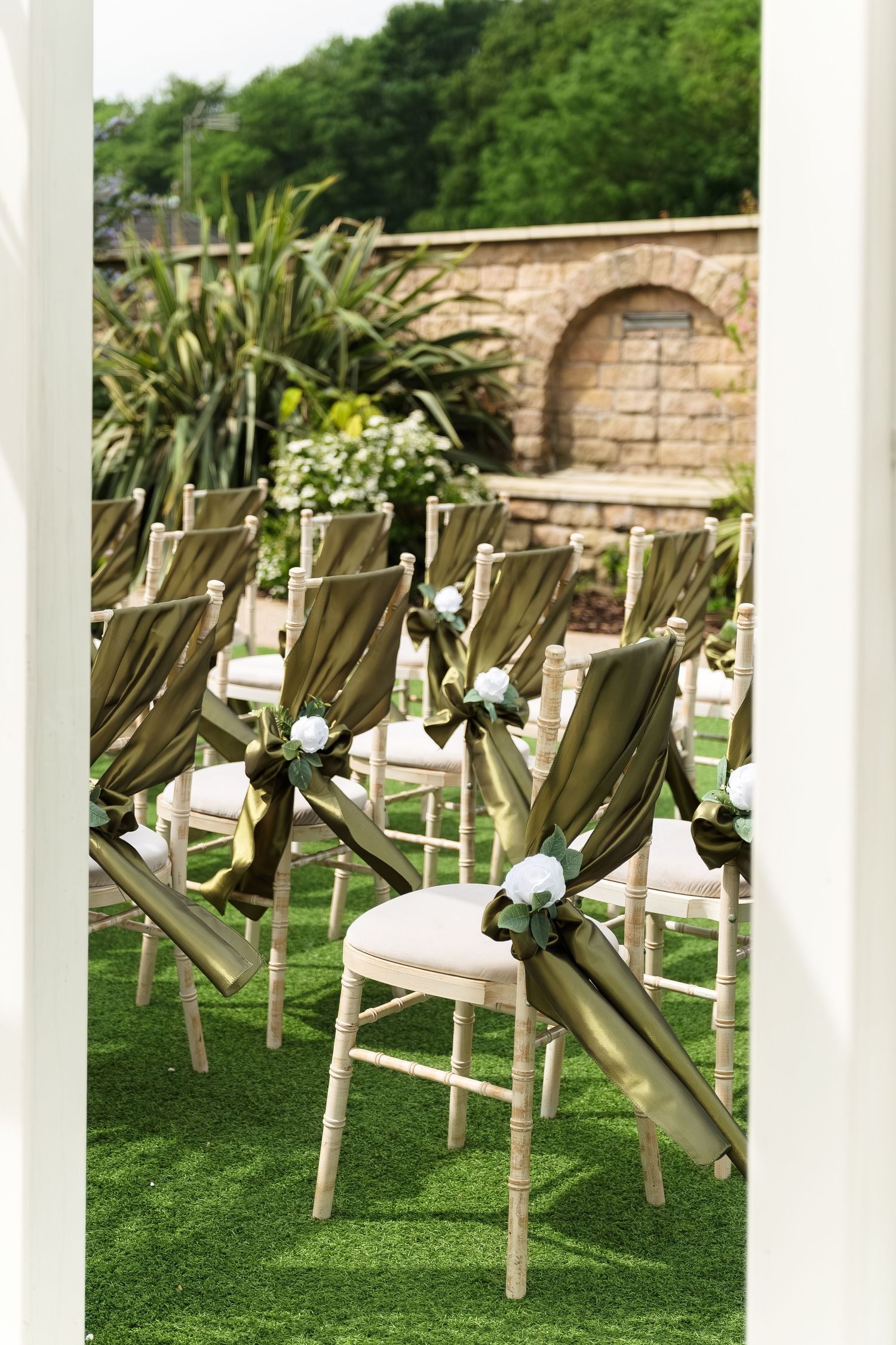 Elegant outdoor wedding ceremony chairs with olive green satin sashes and white roses at Wildes Inn, Chesterfield taken by 21 Photography