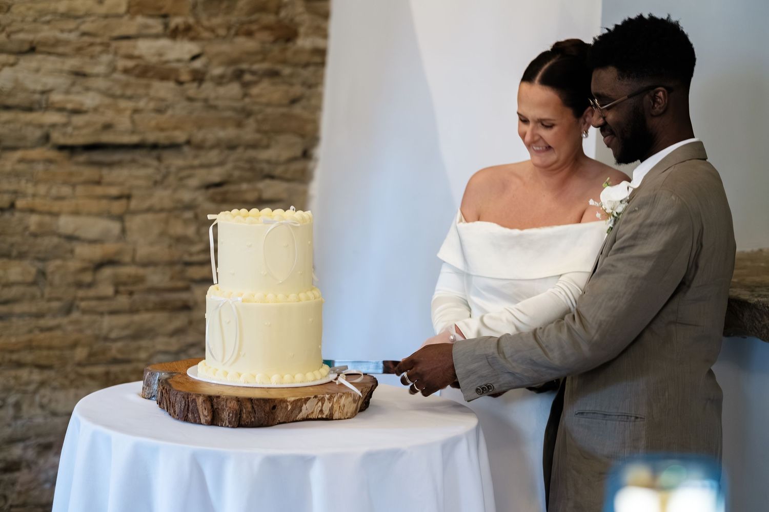 Bride and groom cutting their white two-tier wedding cake together at their elegant rustic wedding reception at dunston hall estate
