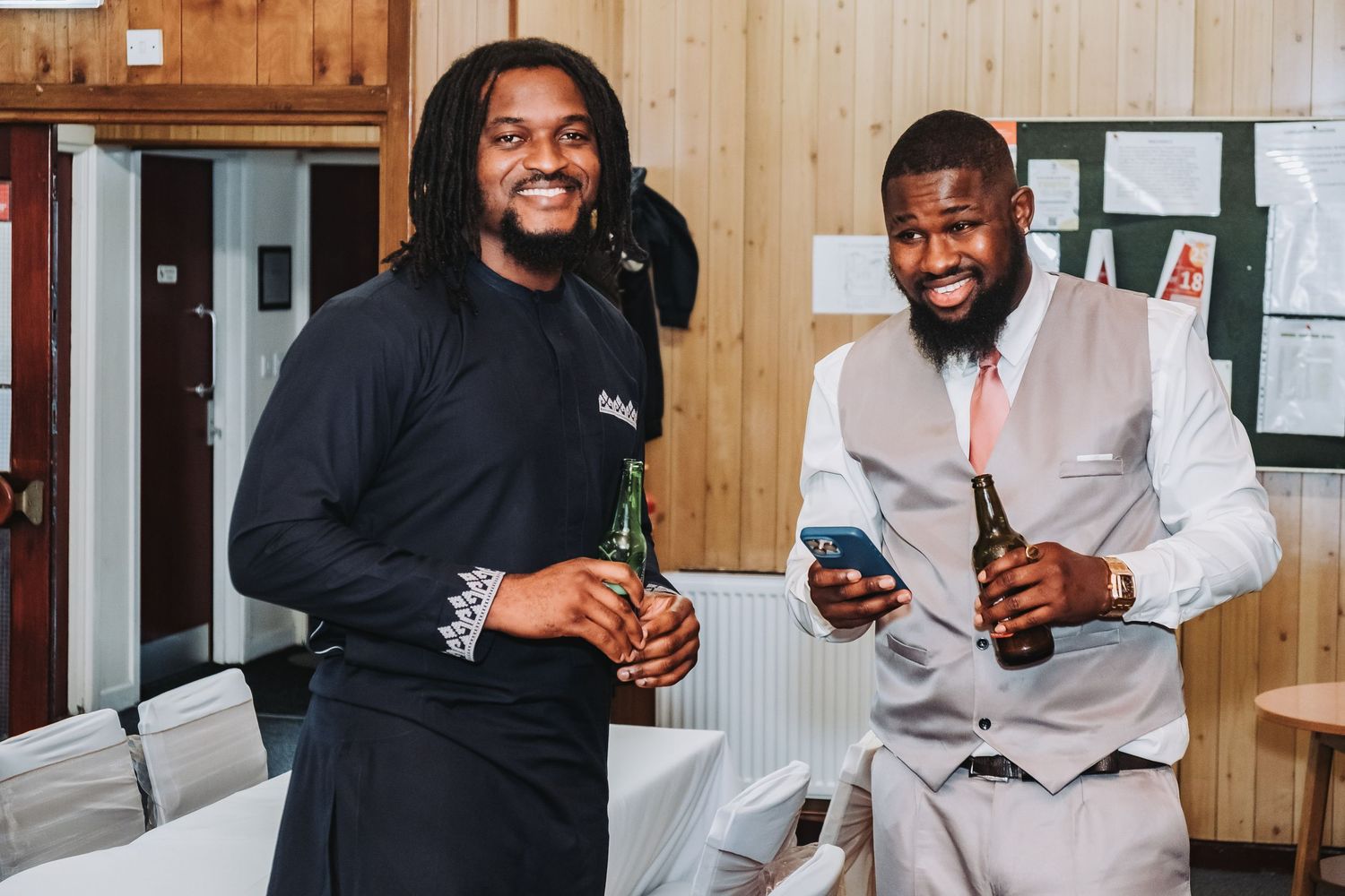 Group of wedding guests smile and celebrate while holding drinks at reception.