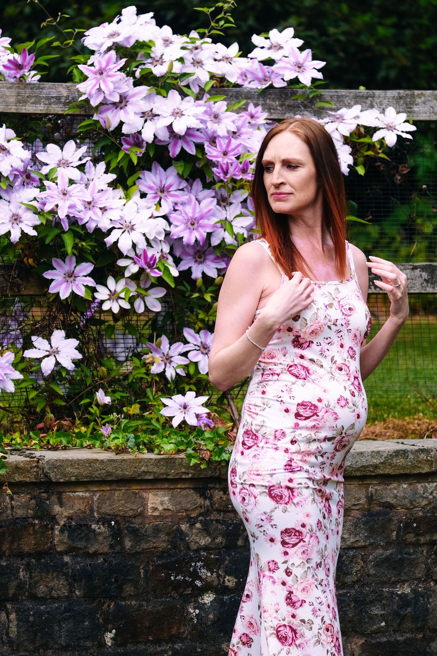 Artistic maternity poses captured against a wall of purple flowering clematis.