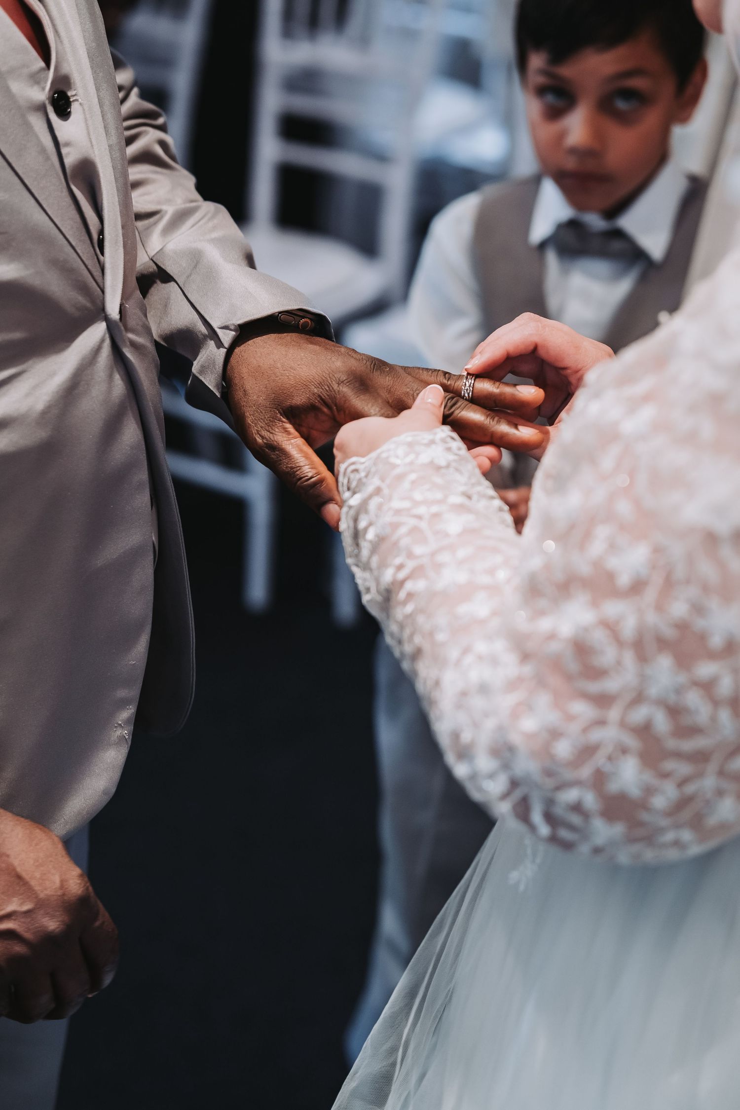 Close-up shot of hands adjusting delicate white lace details on a wedding dress.