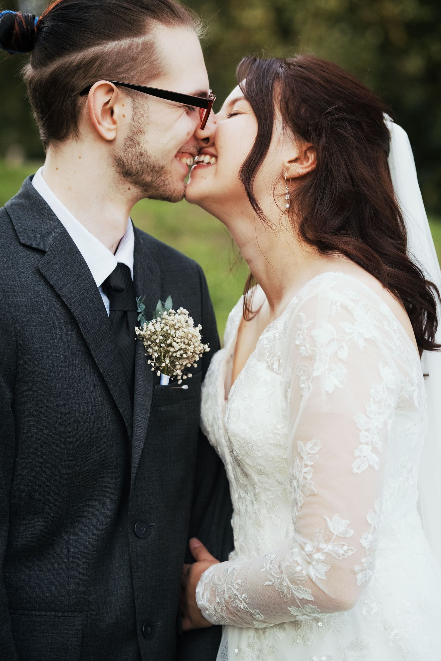 A romantic wedding couple shares intimate kisses while wearing formal attire and baby's breath floral accents.