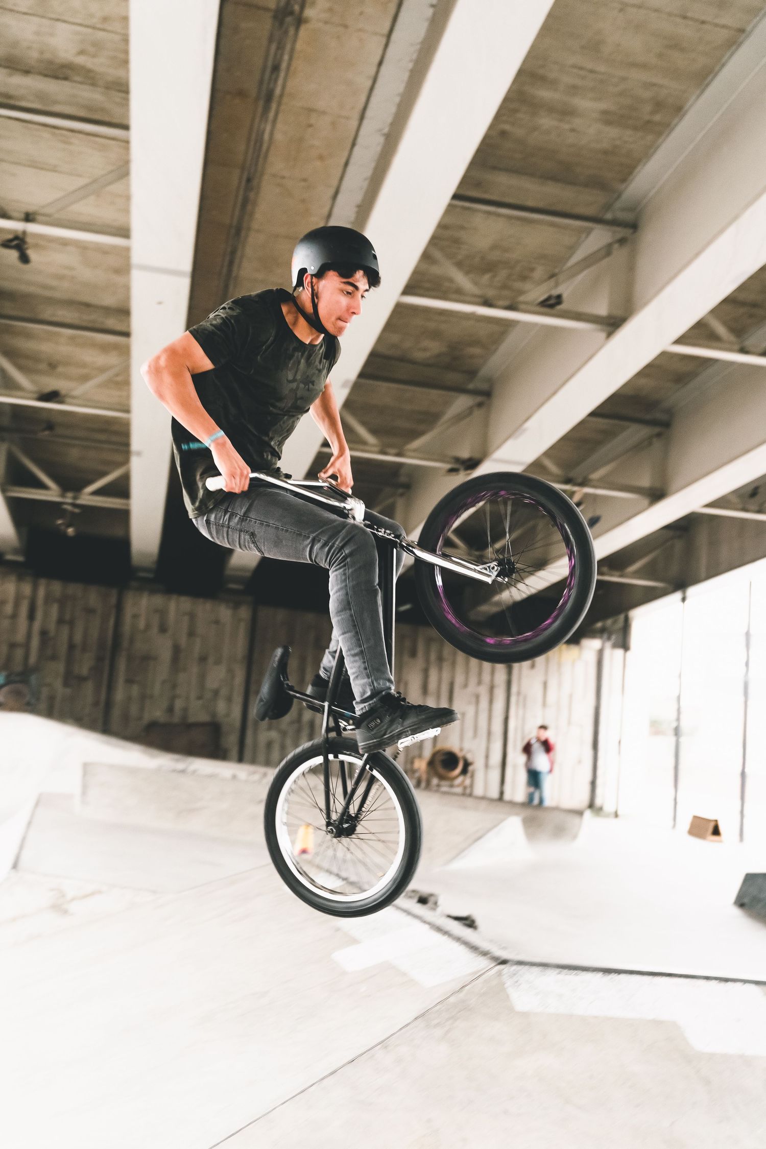 BMX rider performs stylish trick jump on bike in indoor concrete park shot in Leeds by 21 Photography