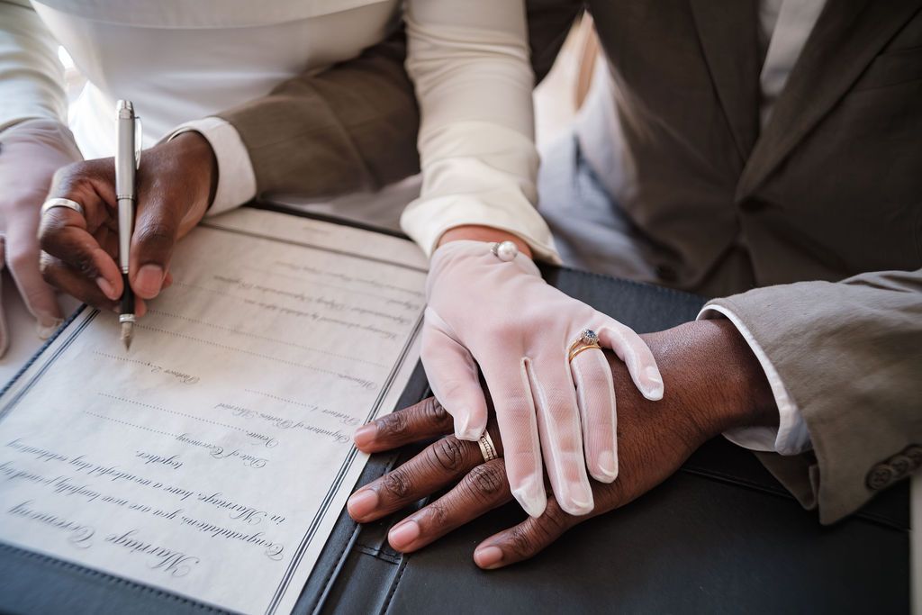 Close up of gloved hands signing the marriage register