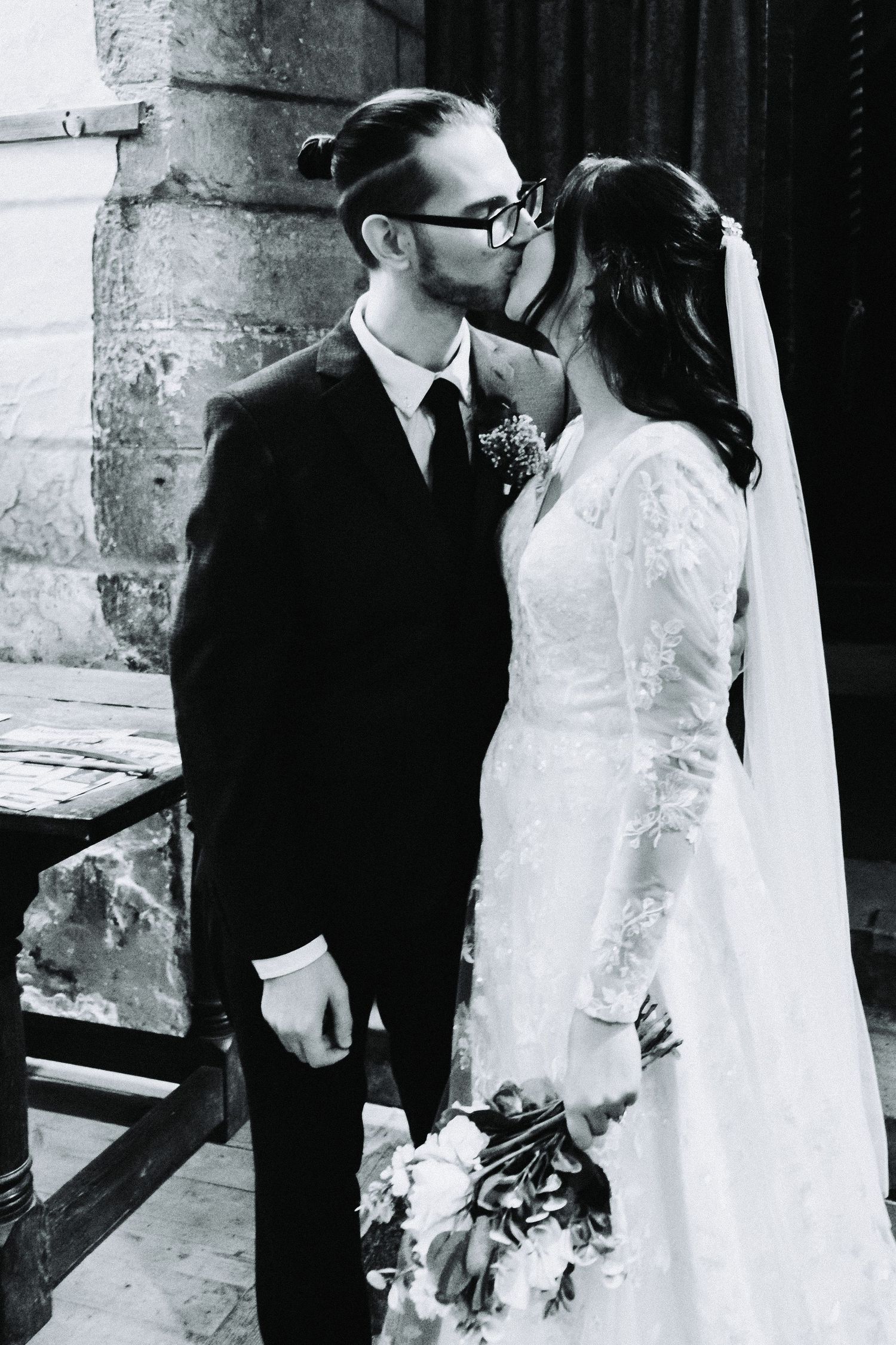 Black and white wedding photos showing tender moments between newlyweds in a rustic setting.