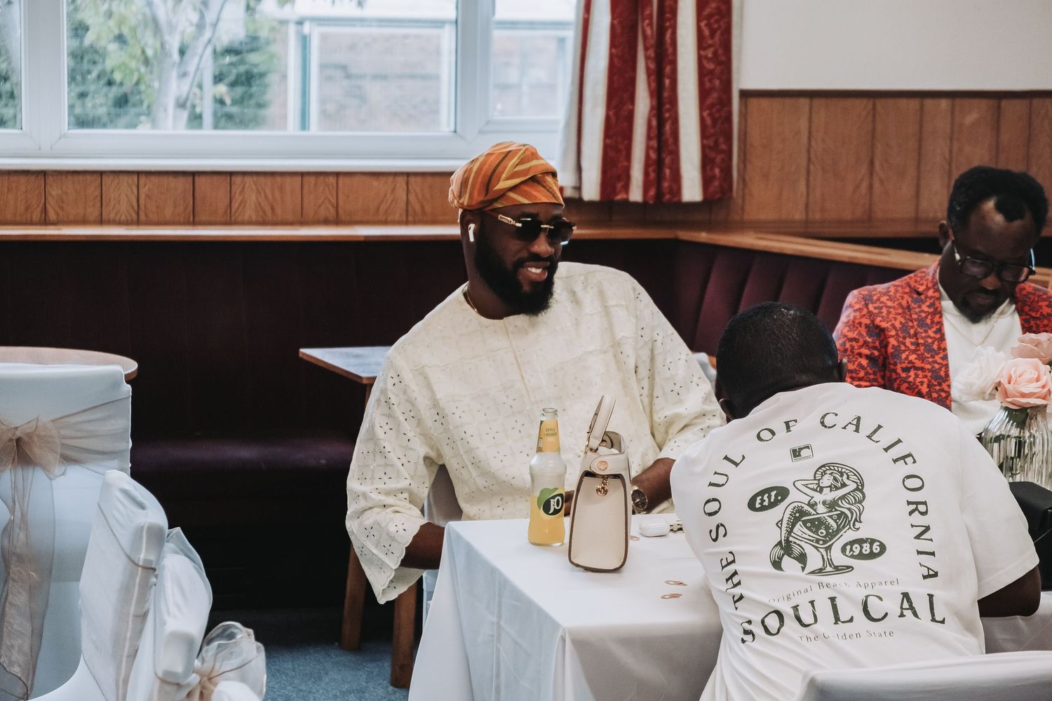 Wedding reception guests in white attire seated at table with Soulcal themed decorations.
