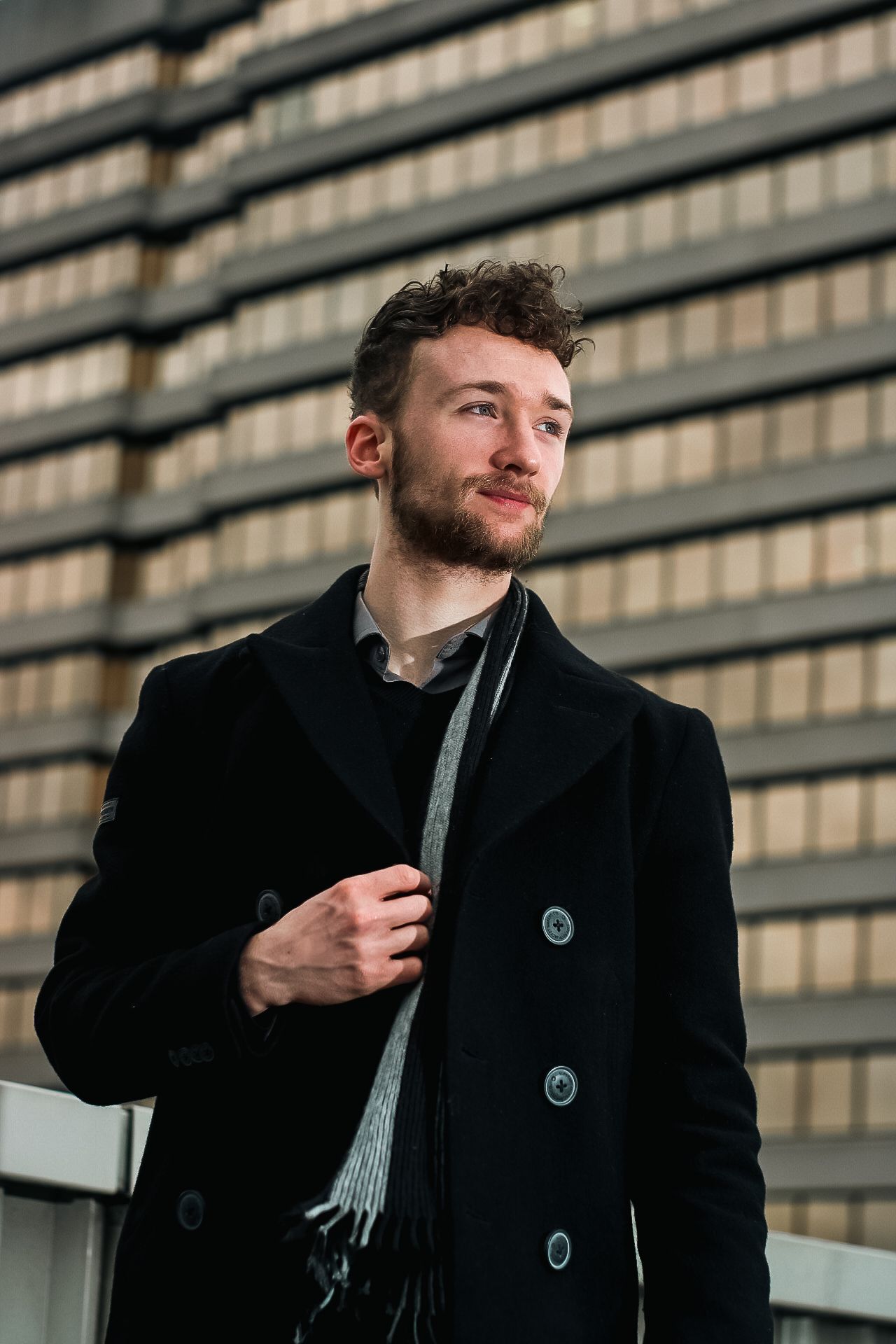 A series of candid black and white photos showing someone in a wool coat and scarf against architectural lines.