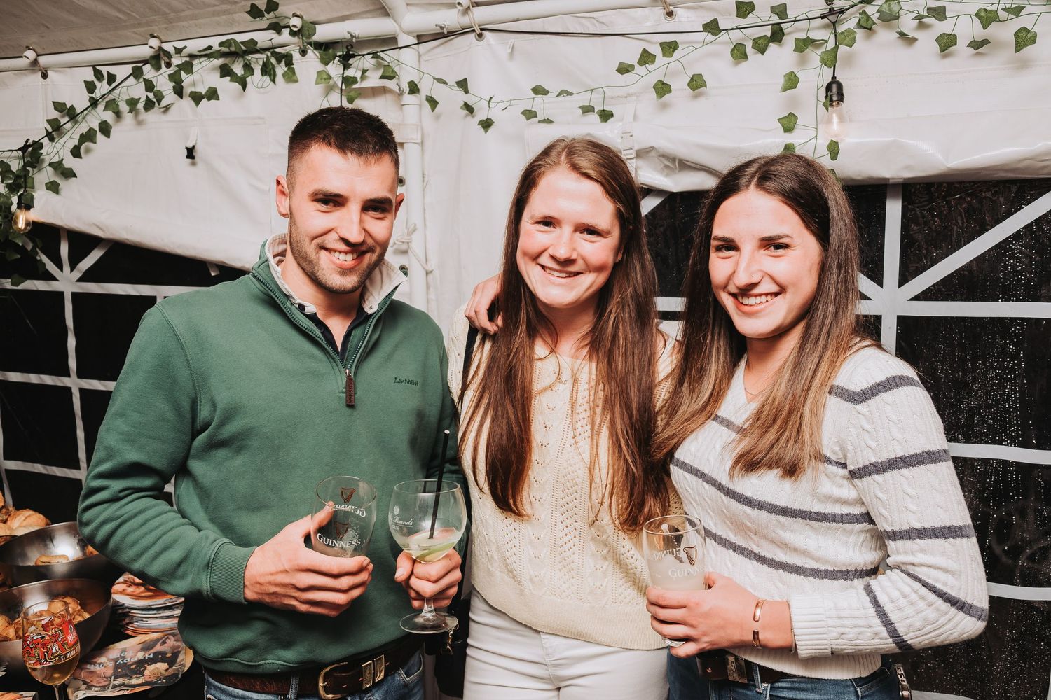 Social gathering with decorative vine elements and people enjoying drinks and conversation.