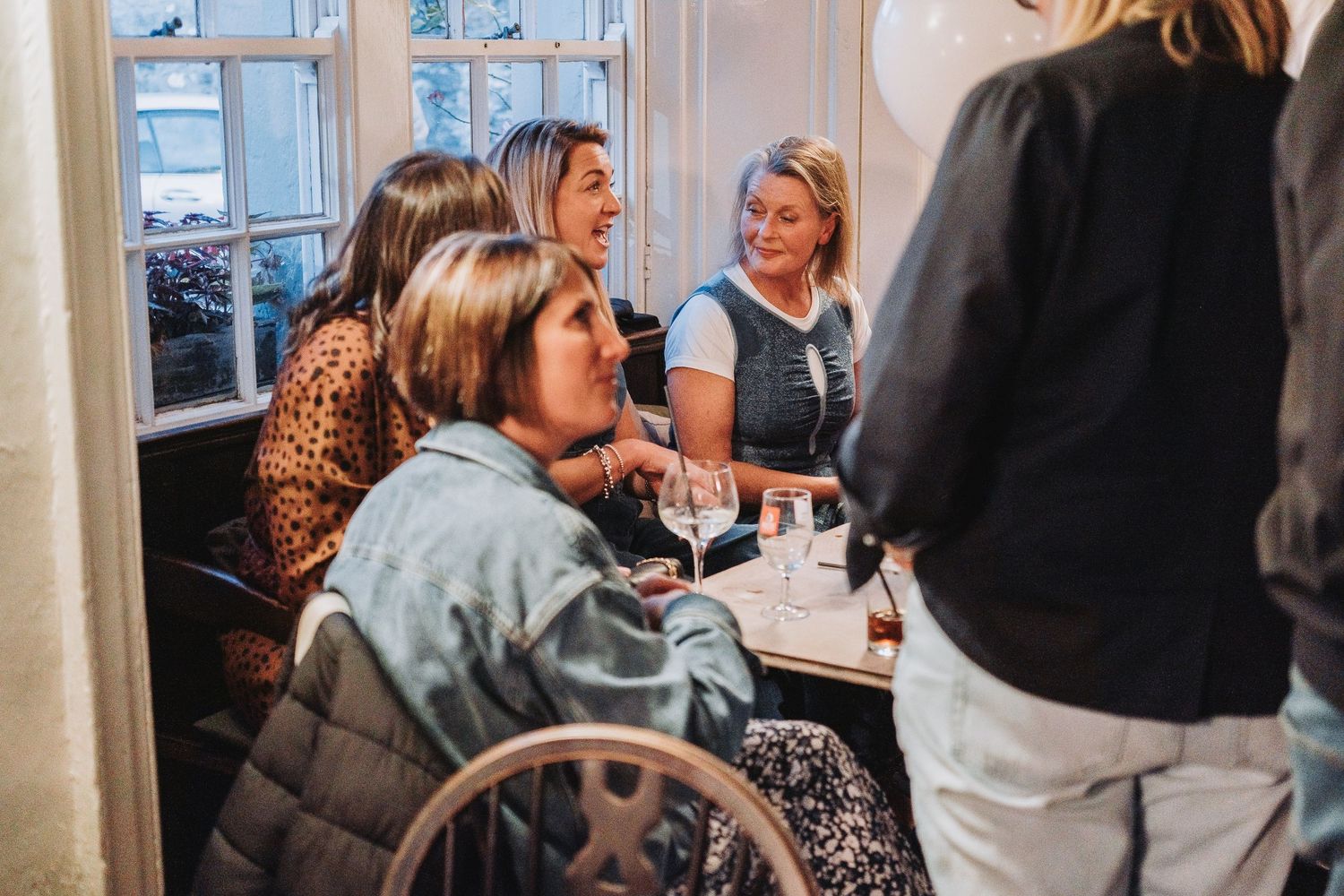 A lively social gathering of guests enjoying drinks and conversation at an indoor event.