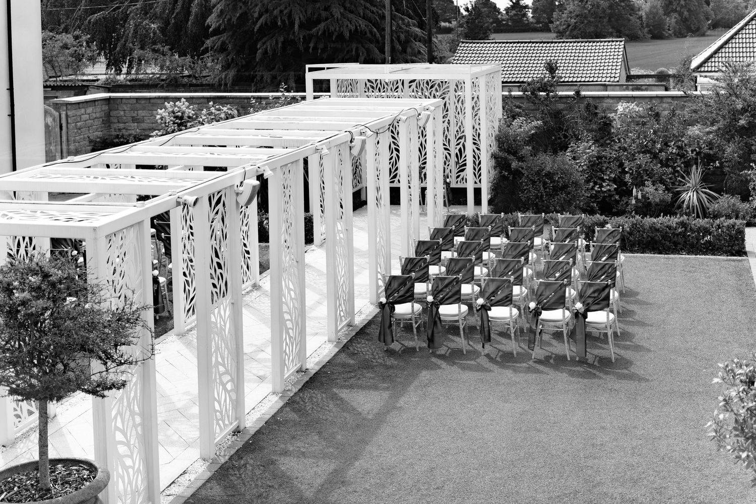 photo of an outdoor wedding ceremony with white pergola and rows of chairs at Wildes Inn, Chesterfield taken by 21 Photography