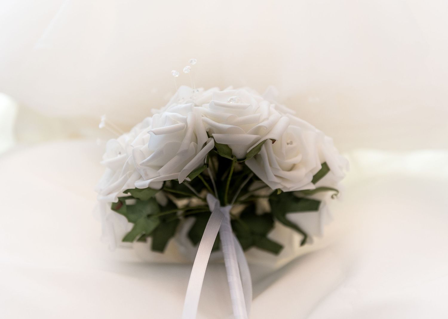 White floral arrangements with ribbons displayed on light background.