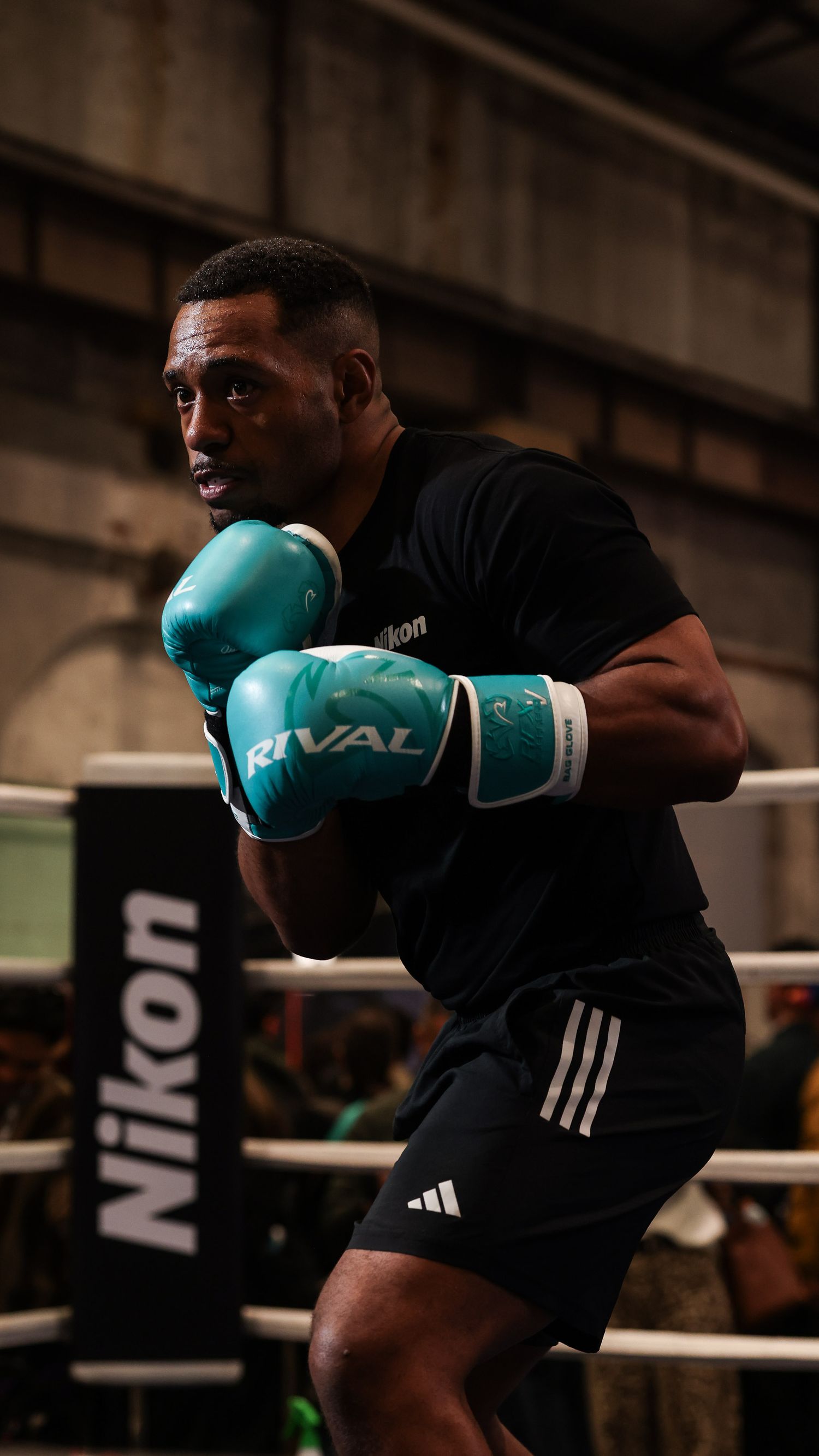 Portrait taken by Chapter Portraits Melbourne of a boxer in a black shirt throws punches during an indoor training session