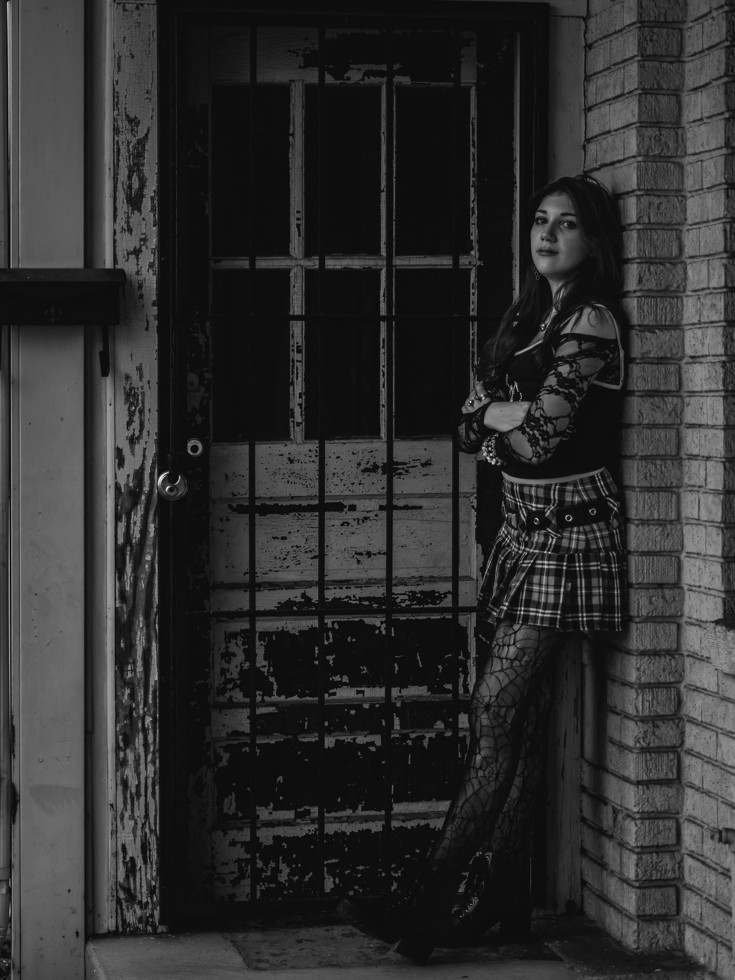 Artistic black and white portrait by vintage metal door and brick wall.