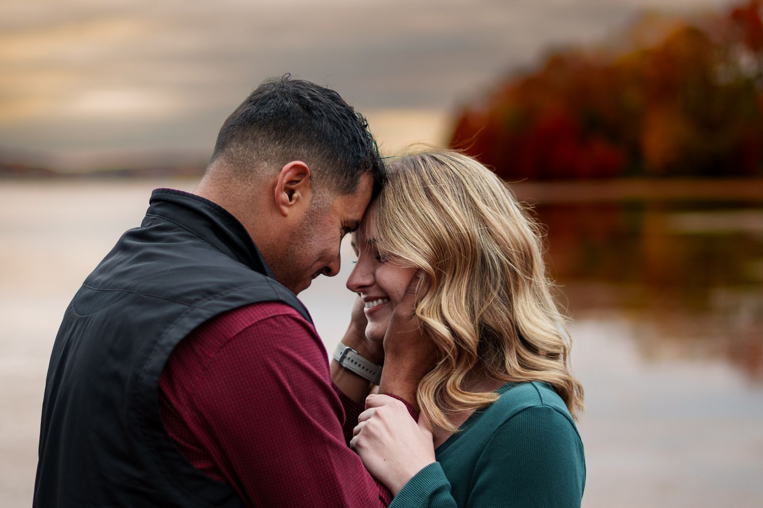 Intimate lakeside portrait session with autumn foliage and moody skies.