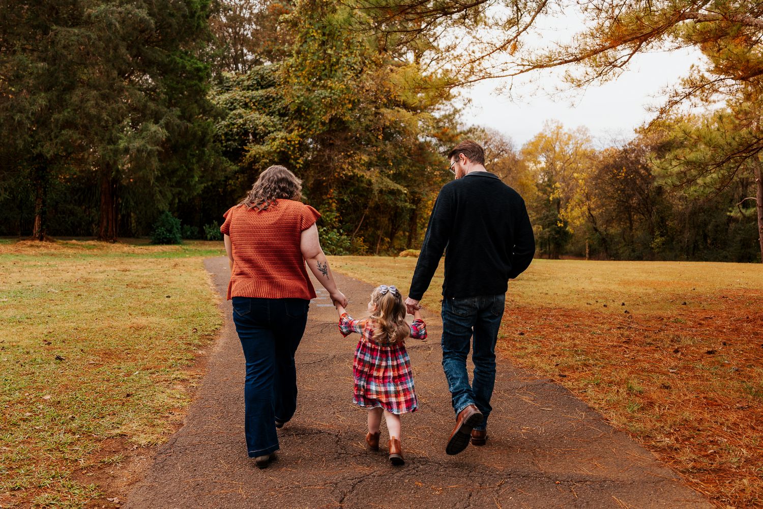 Family strolling together on a winding path through fall foliage.