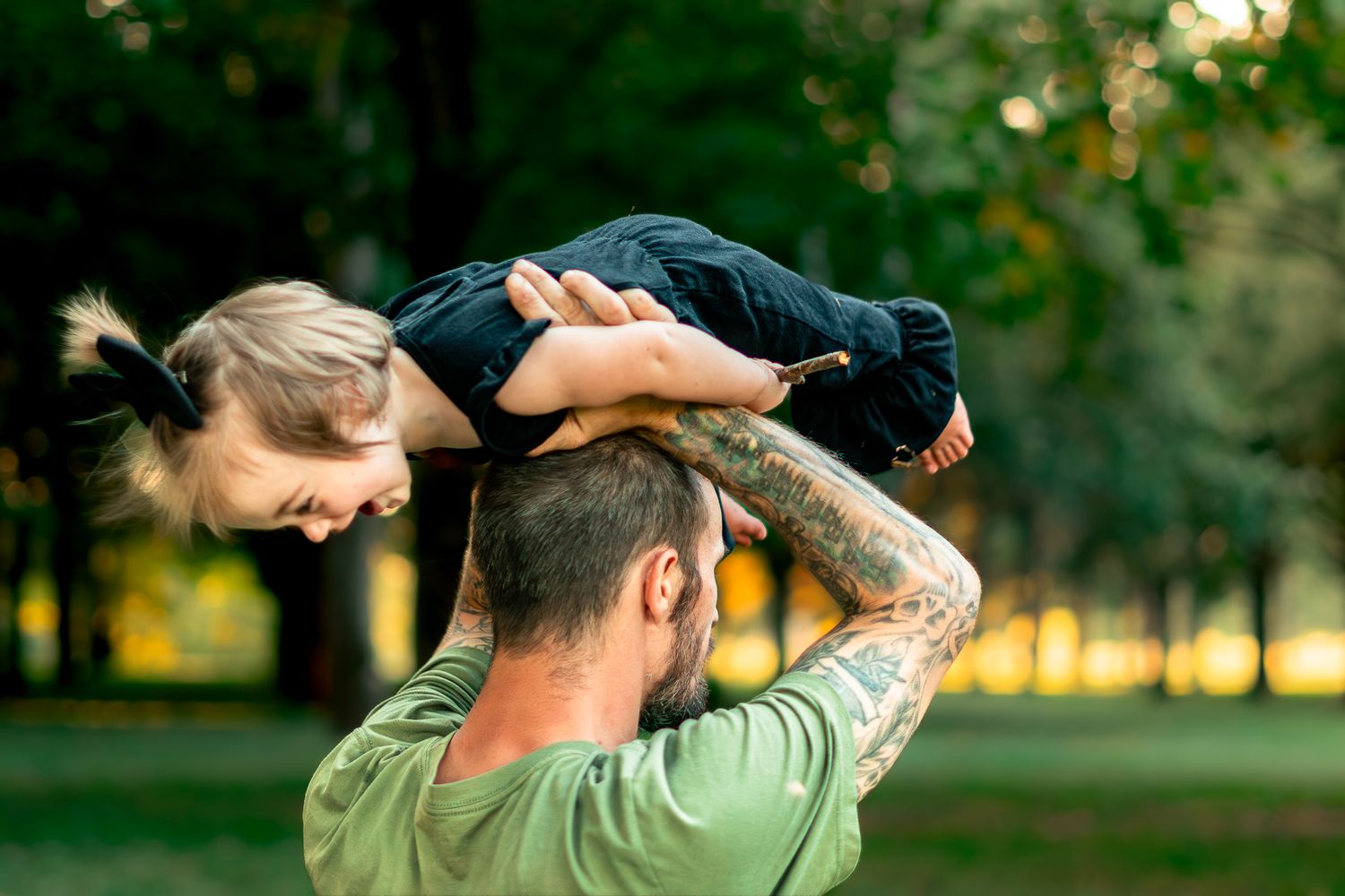Family enjoying a playful moment together in a park during golden hour.