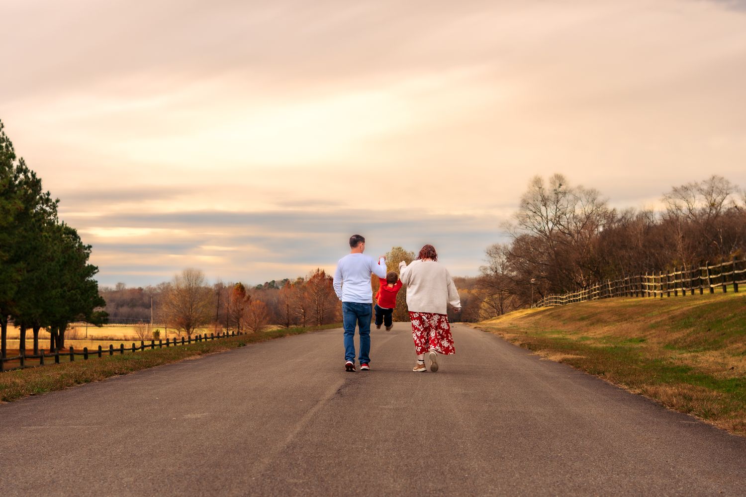 Family walking together on a paved path at sunset with warm golden light illuminating the landscape.