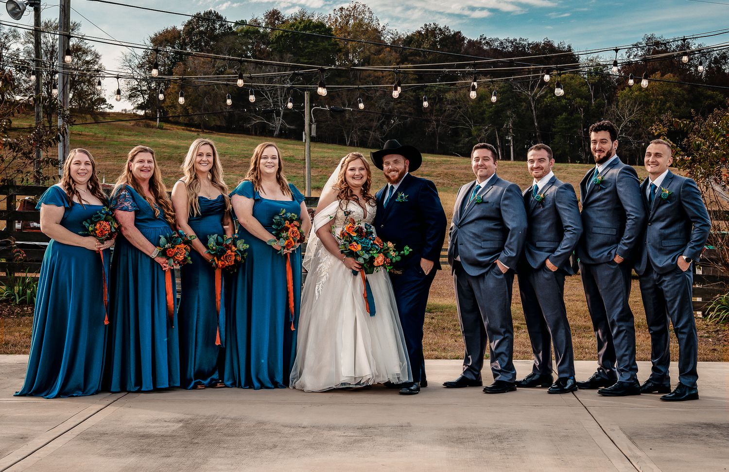 Wedding party lined up wearing navy blue attire on concrete patio.