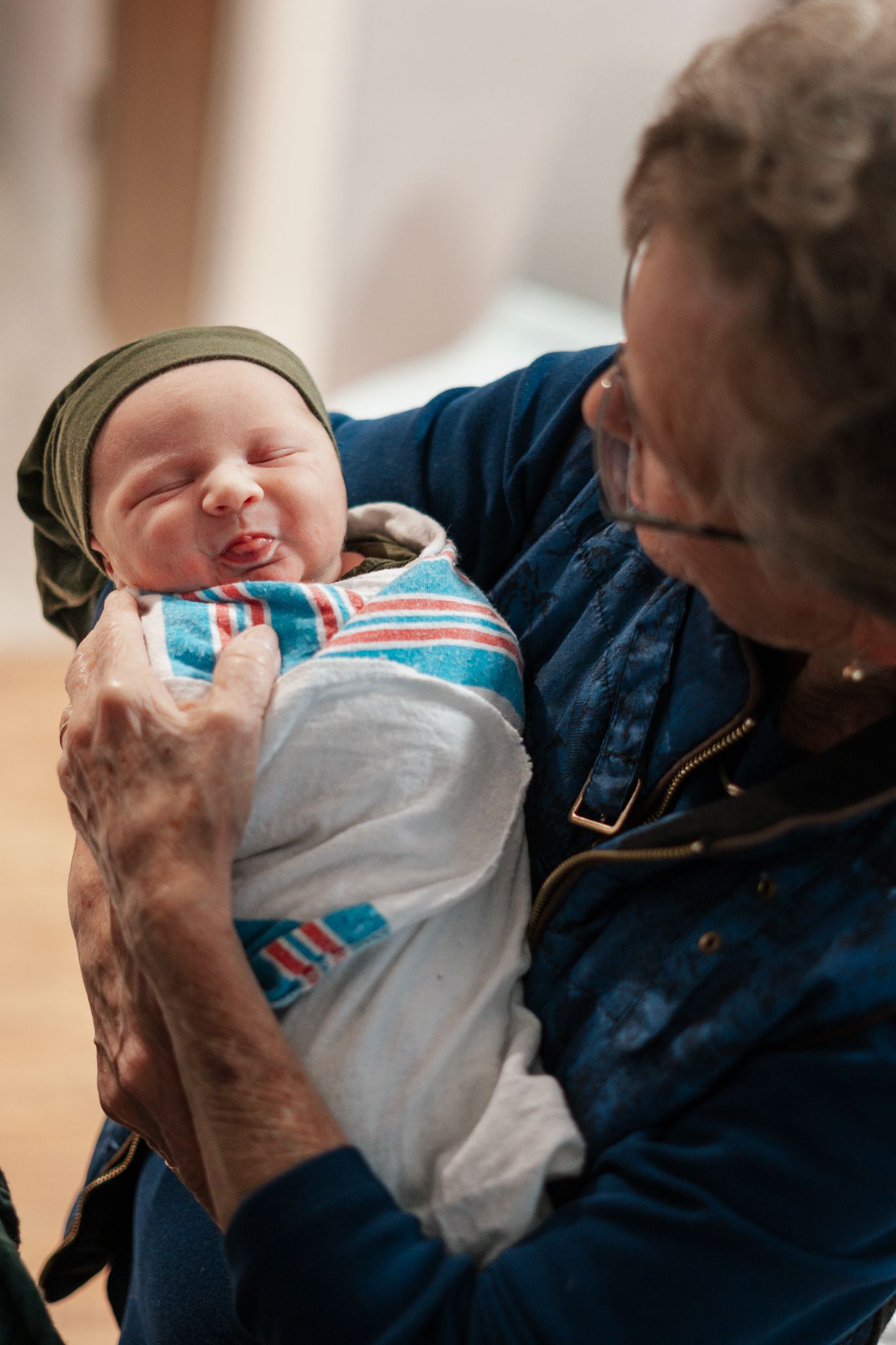 Gentle moment with a newborn wearing blue and white striped clothing.