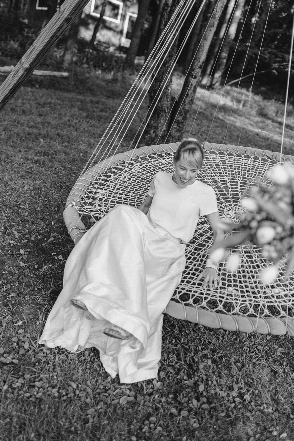 A sequence of vintage black and white photos showing a child relaxing in a woven peacock chair outdoors.