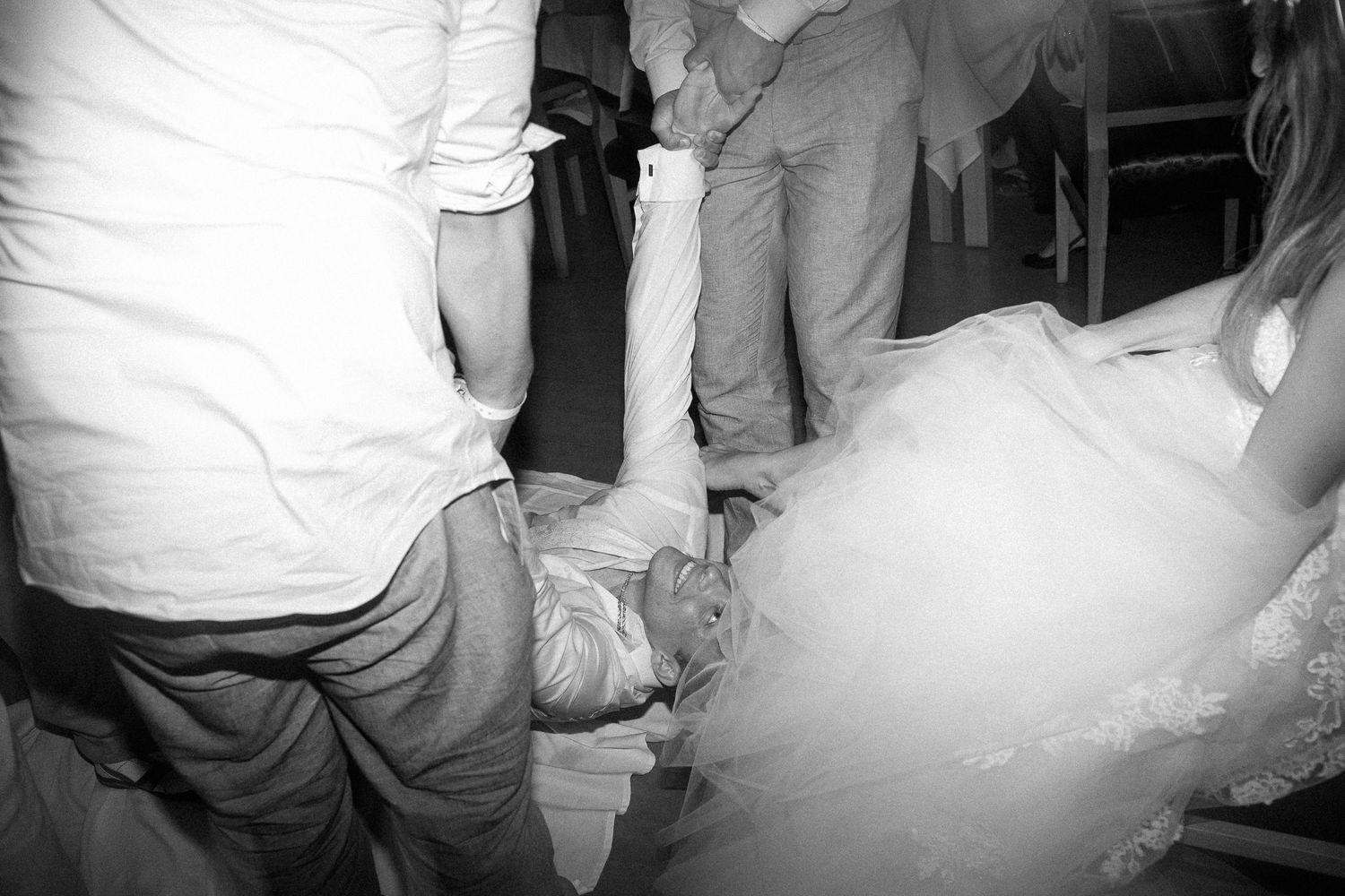 Black and white photo of wedding guests dancing energetically on the dance floor during reception celebration.