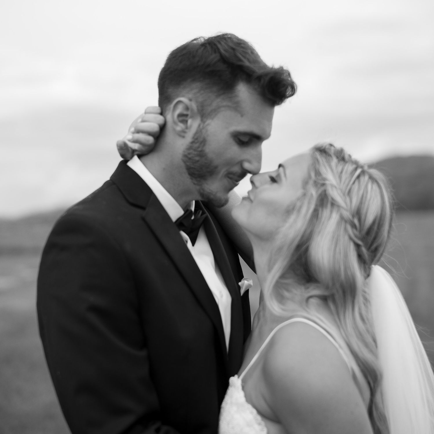 Romantic black and white wedding portraits showing intimate moments on a hillside.