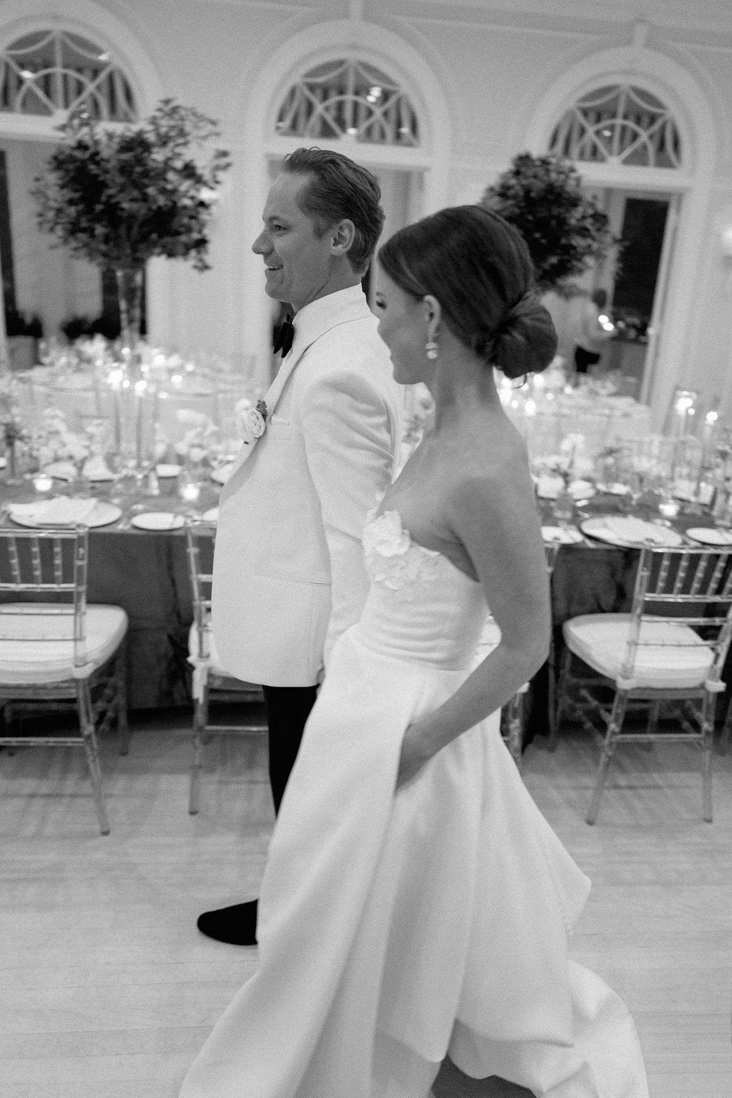 A black and white wedding reception photo showing couples dancing together on an elegant ballroom floor.