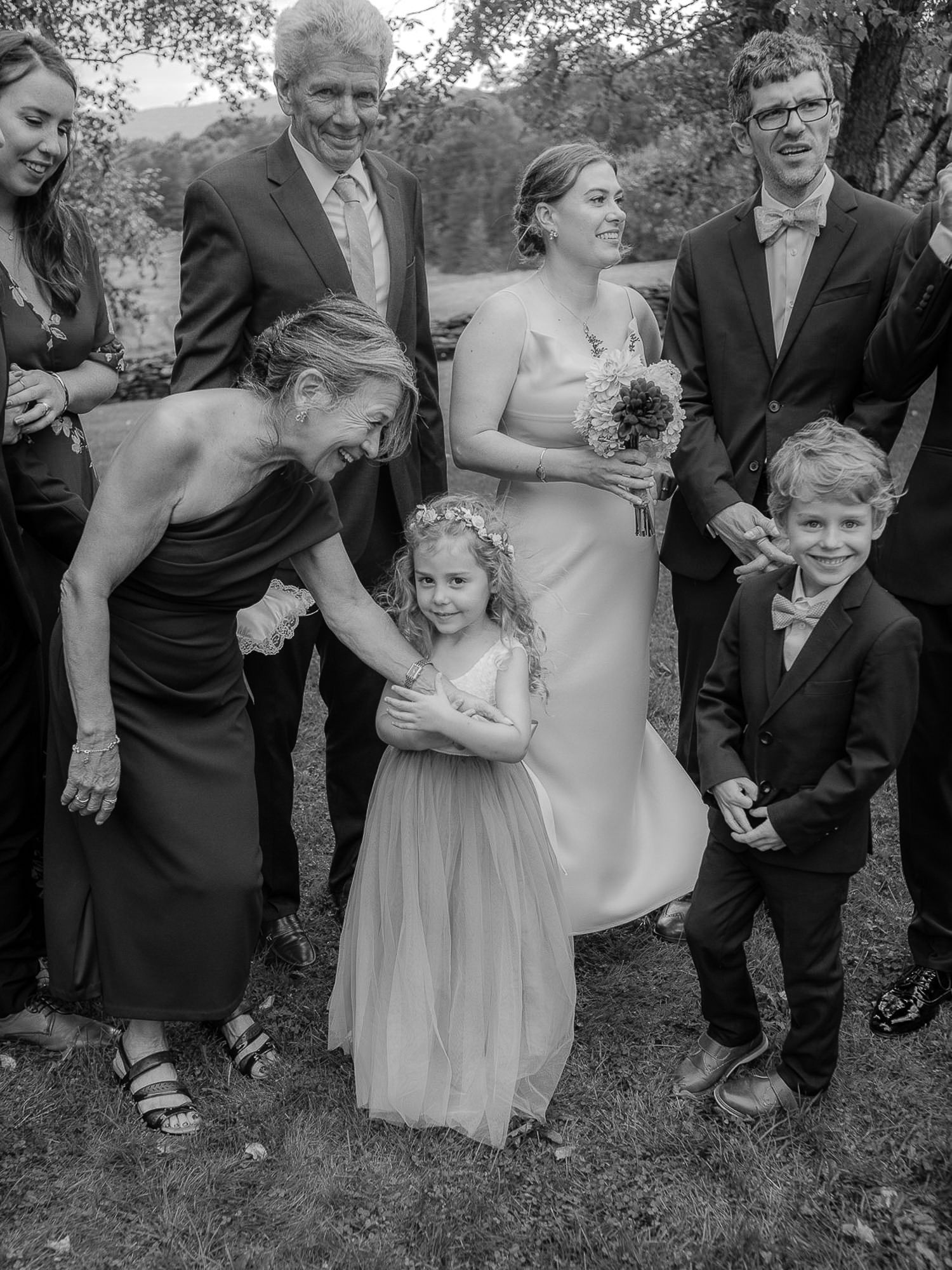 Black and white candid wedding photos showing joyful interactions between wedding party members during outdoor celebration.