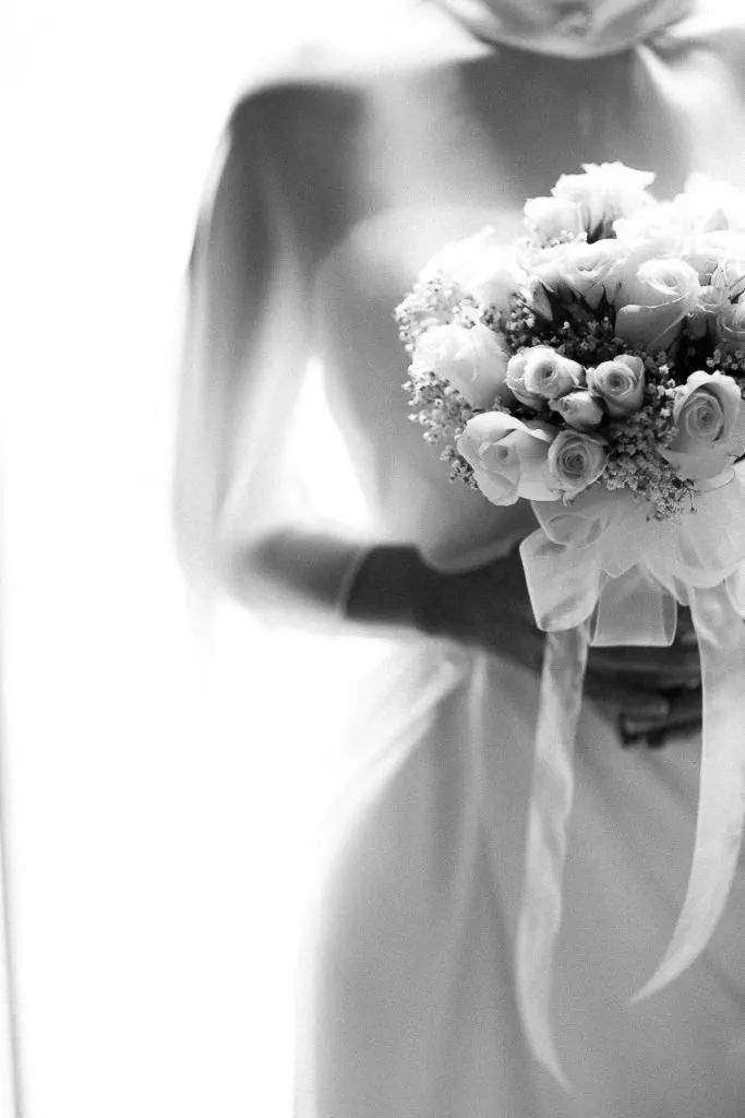 Row of delicate white rose bouquets with ribbons in soft focus.