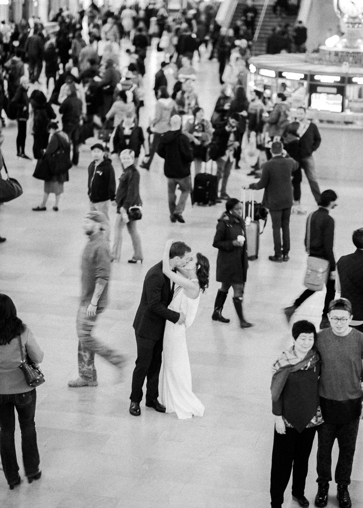 Black and white wide shot of a crowded reception venue with dancing couples.
