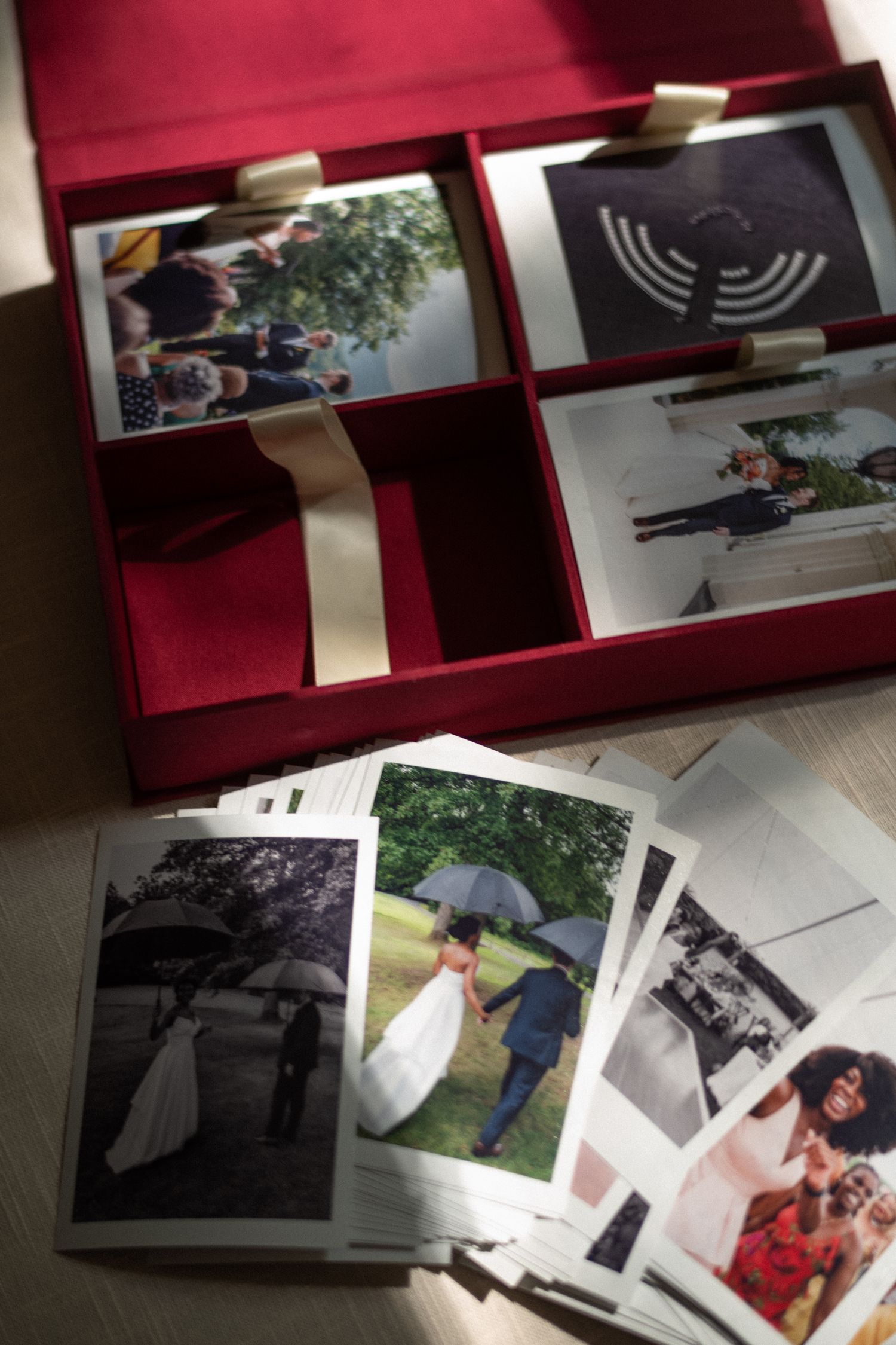Collection of wedding photographs arranged in a red presentation box with ribbon detail.