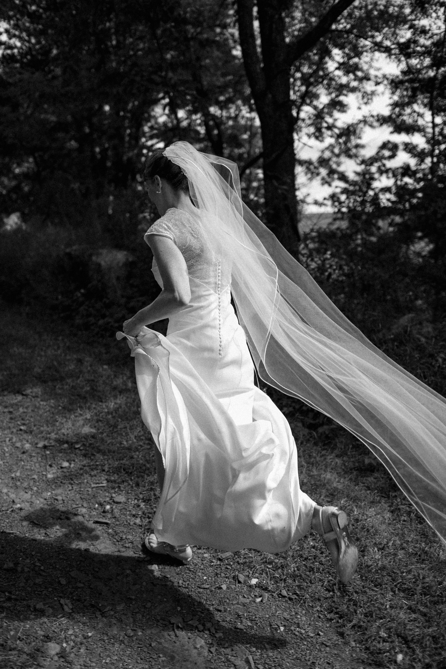A flowing white wedding dress and veil create an ethereal movement sequence in a black and white forest setting.