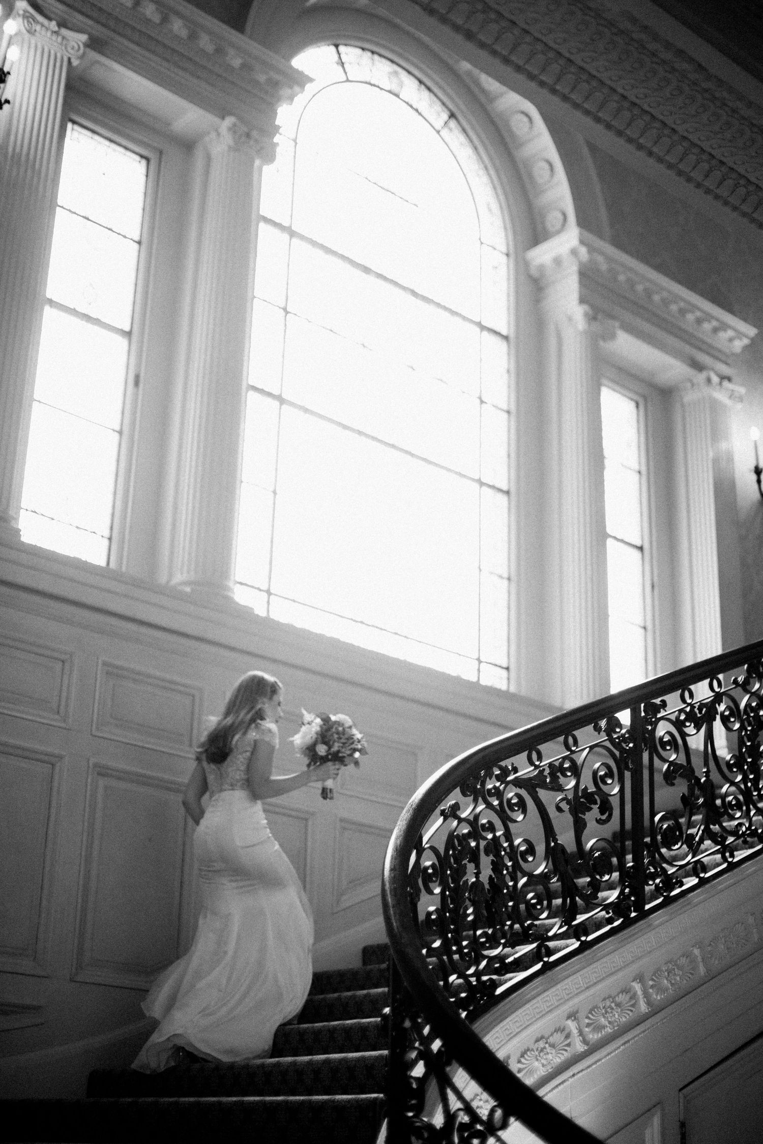 Black and white photos show a bride ascending an ornate staircase with dramatic natural lighting.