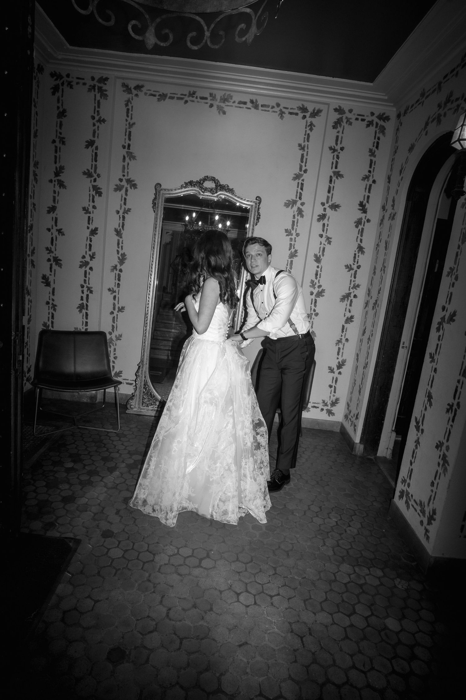 Black and white photo of a bride and groom sharing a first dance in an elegant vintage ballroom.