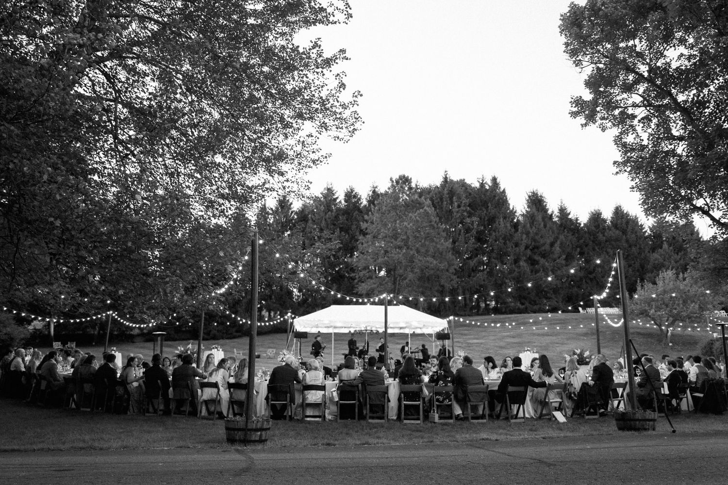 Panoramic view of an outdoor wedding reception setup with tents and trees.