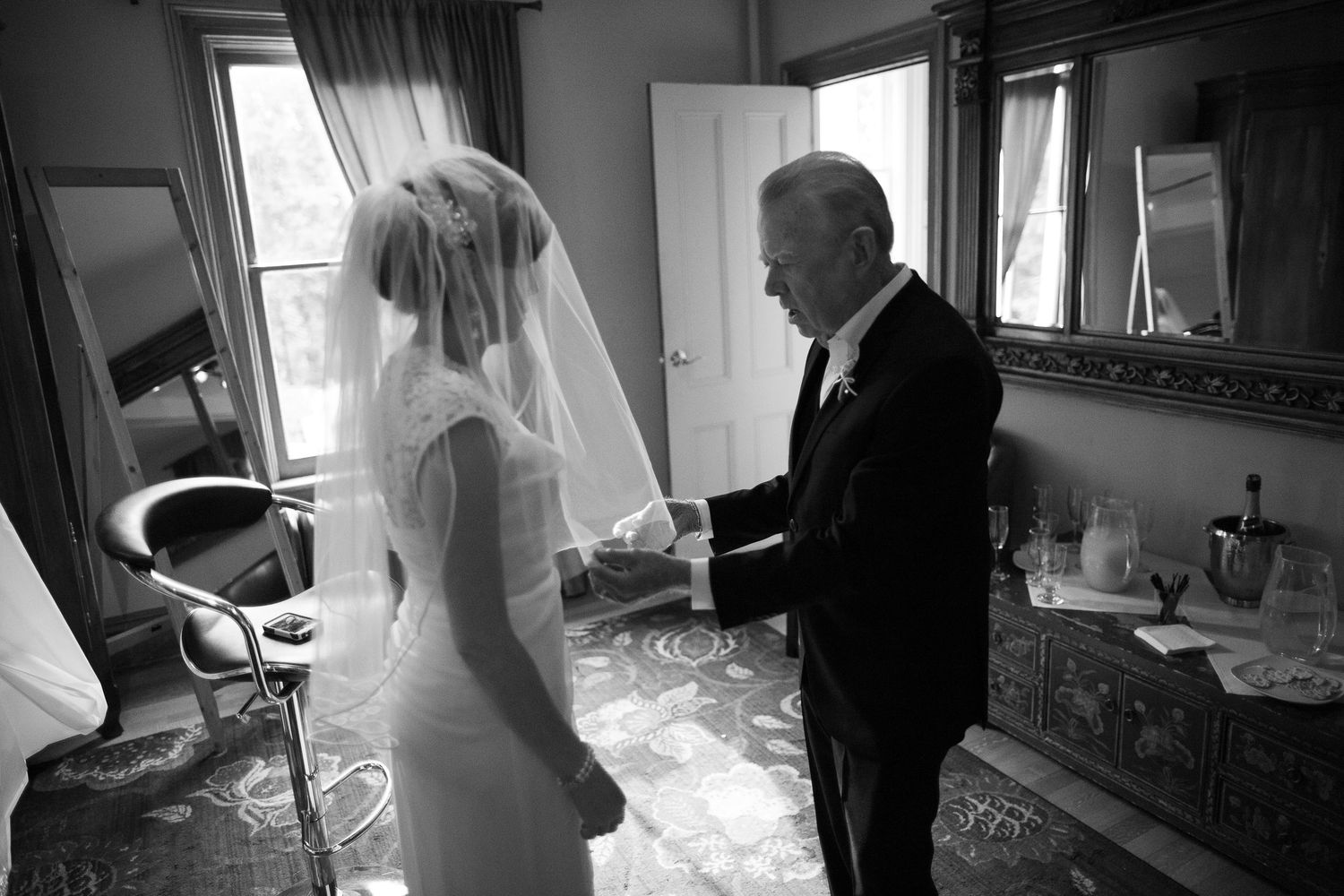 Black and white photo of a bride and her father sharing a tender moment before the wedding ceremony.