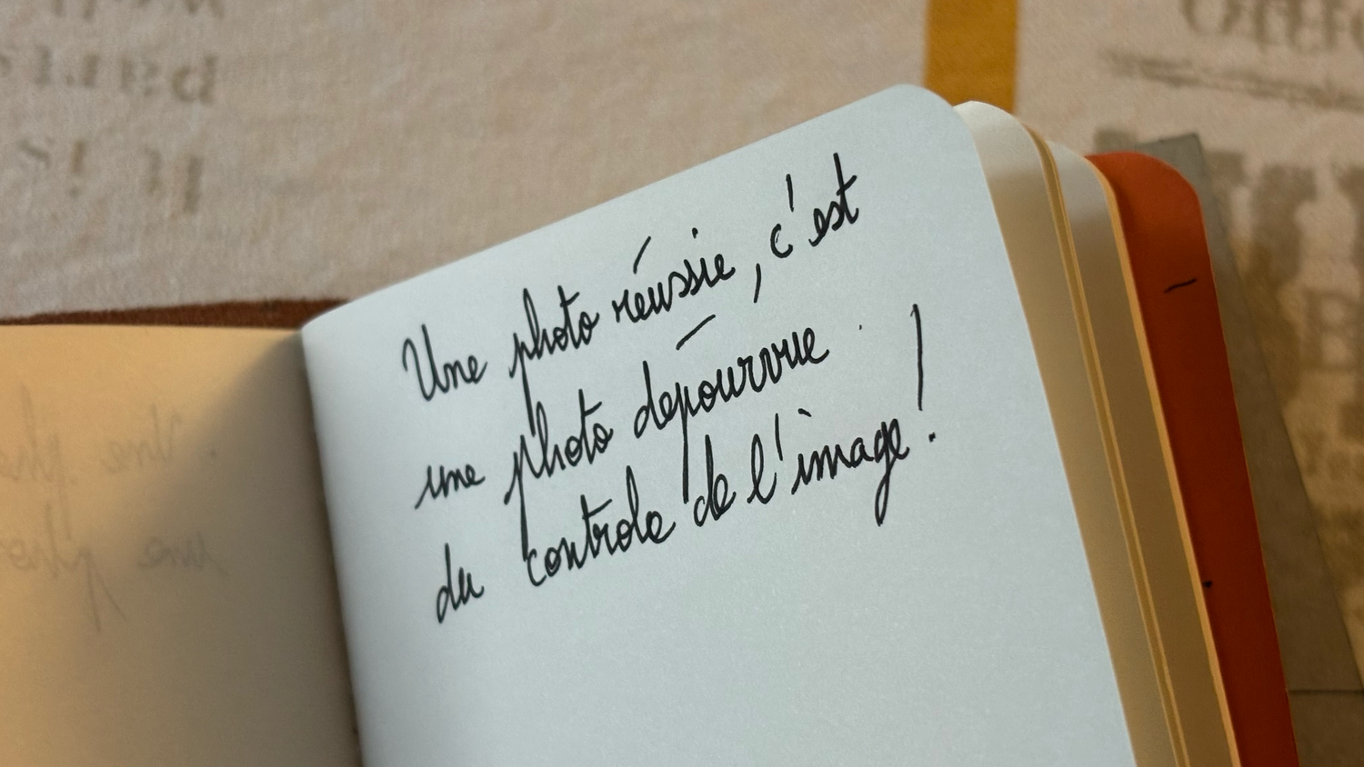 Open notebook with French handwritten quote about photography in black ink on white pages.