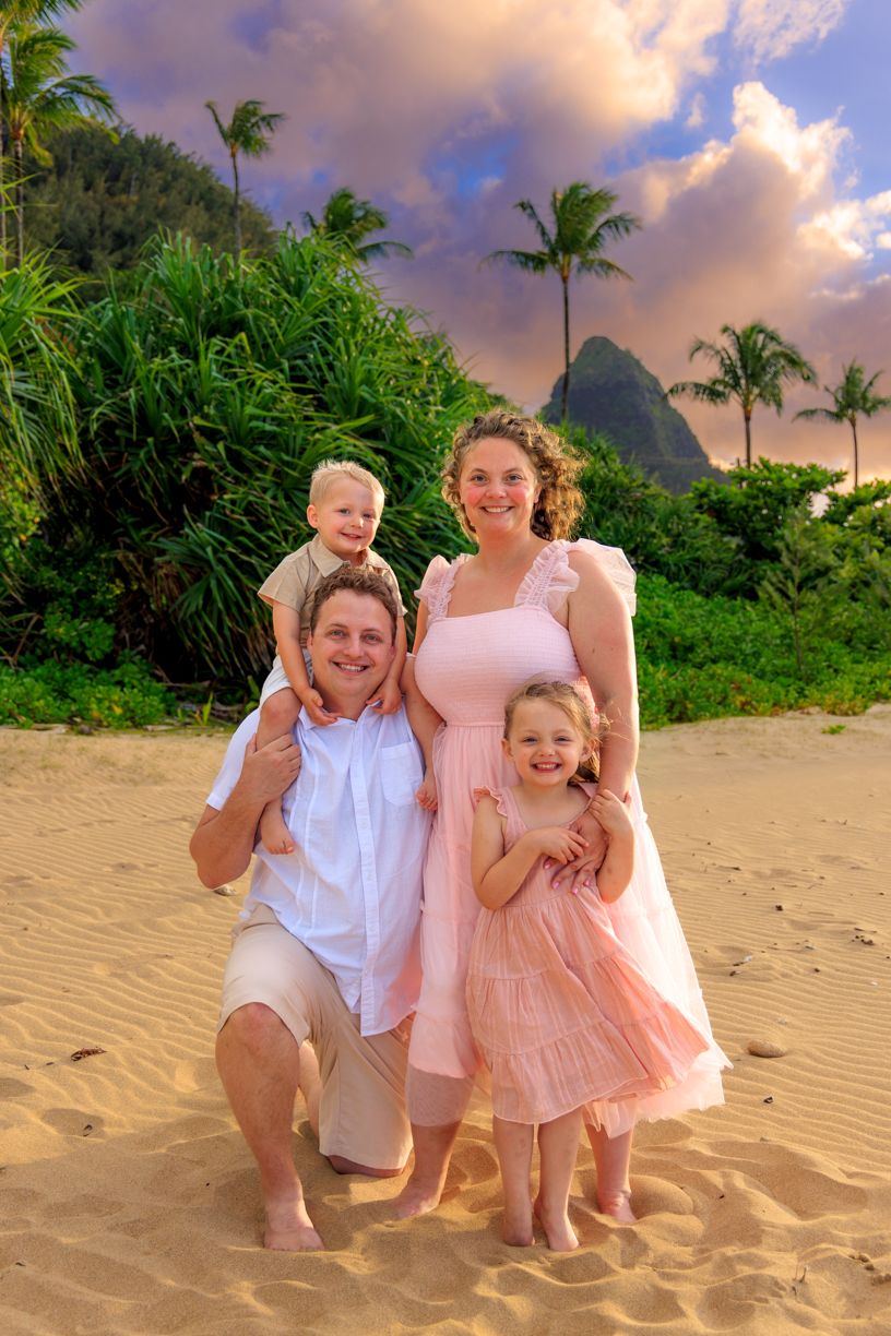 A joyful beach photoshoot at sunset with palm trees and golden sand in Hawaii.