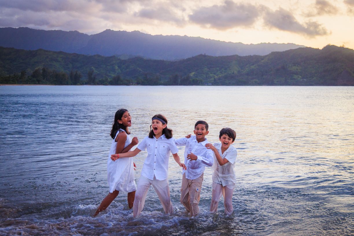Family playing and splashing in ocean water during sunset photo session.