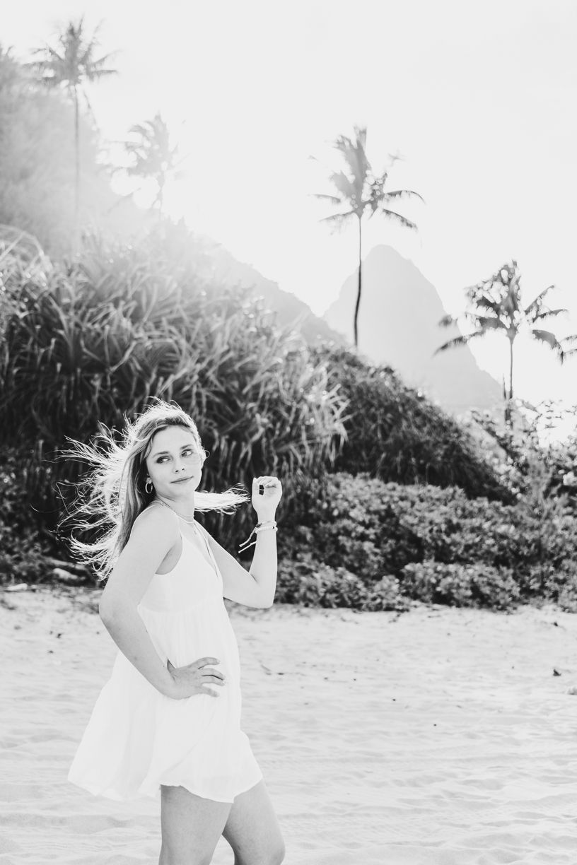 Black and white beach portrait with palm trees and mountains in Hawaii.