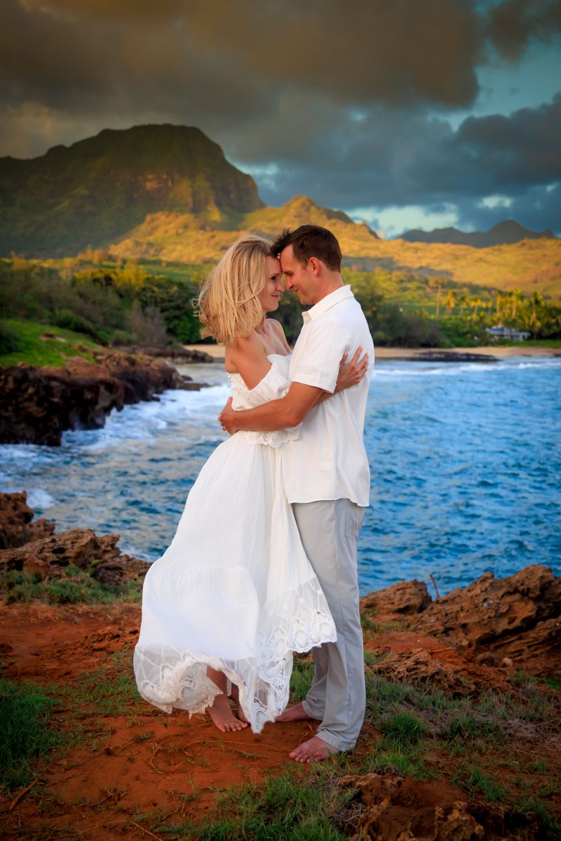 Romantic photoshoot on rocky coastline with dramatic blue ocean waves.