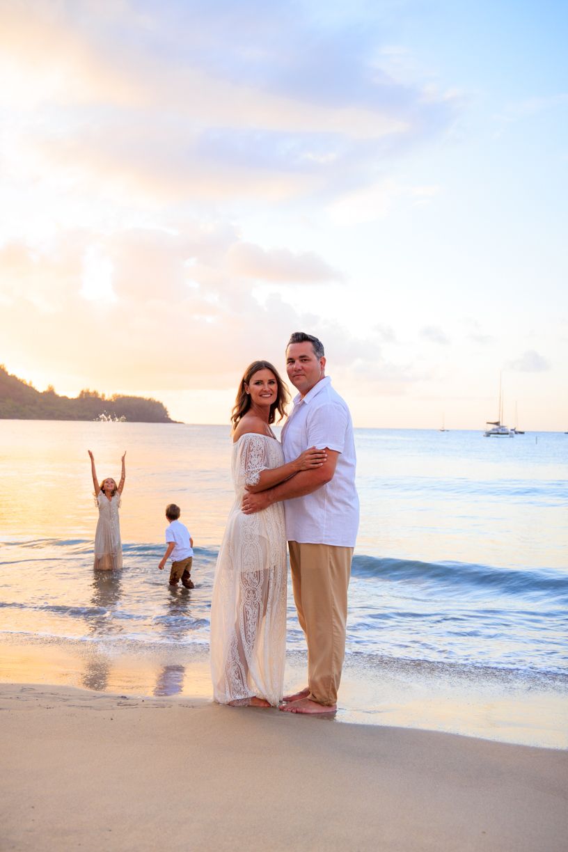 Couple shares romantic moments on a beautiful beach at sunset with palm trees and ocean waves in Hawaii.