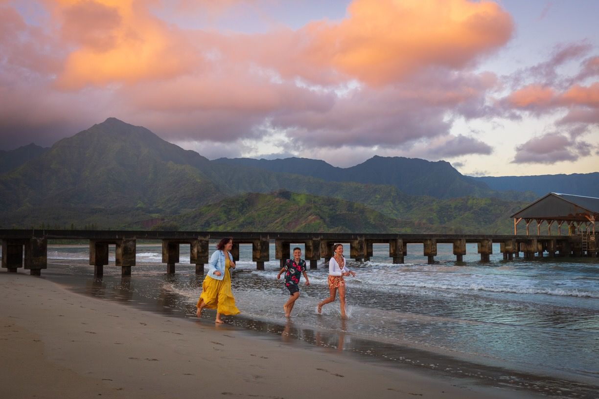 Scenic beach landscape at sunset with mountains and pier in Hawaii.