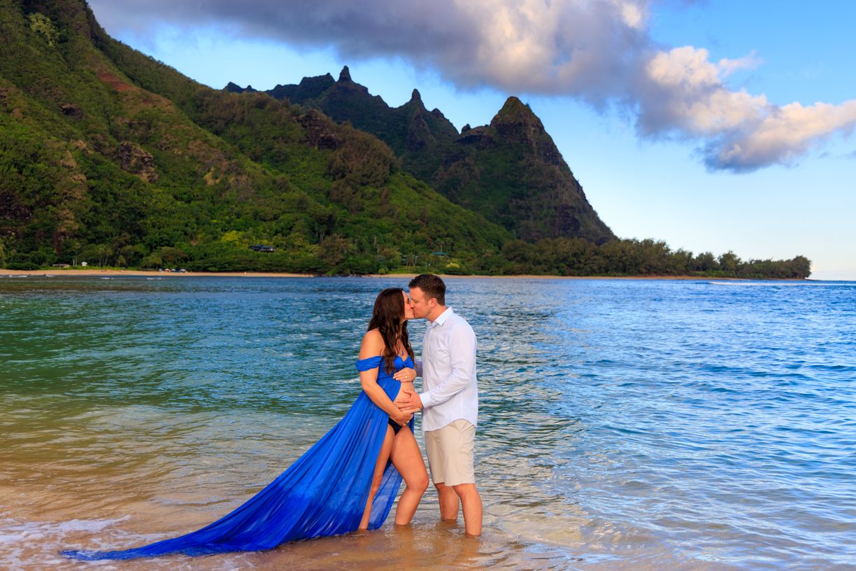 Scenic beach maternity photos with dramatic mountain landscape and crystal clear waters.