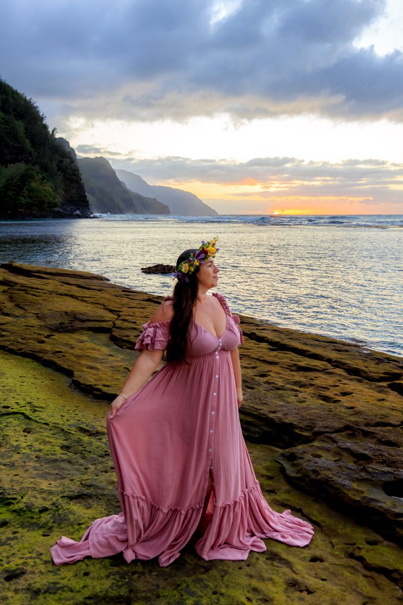 Dramatic coastal landscape with pink dress flowing in the wind at sunset.