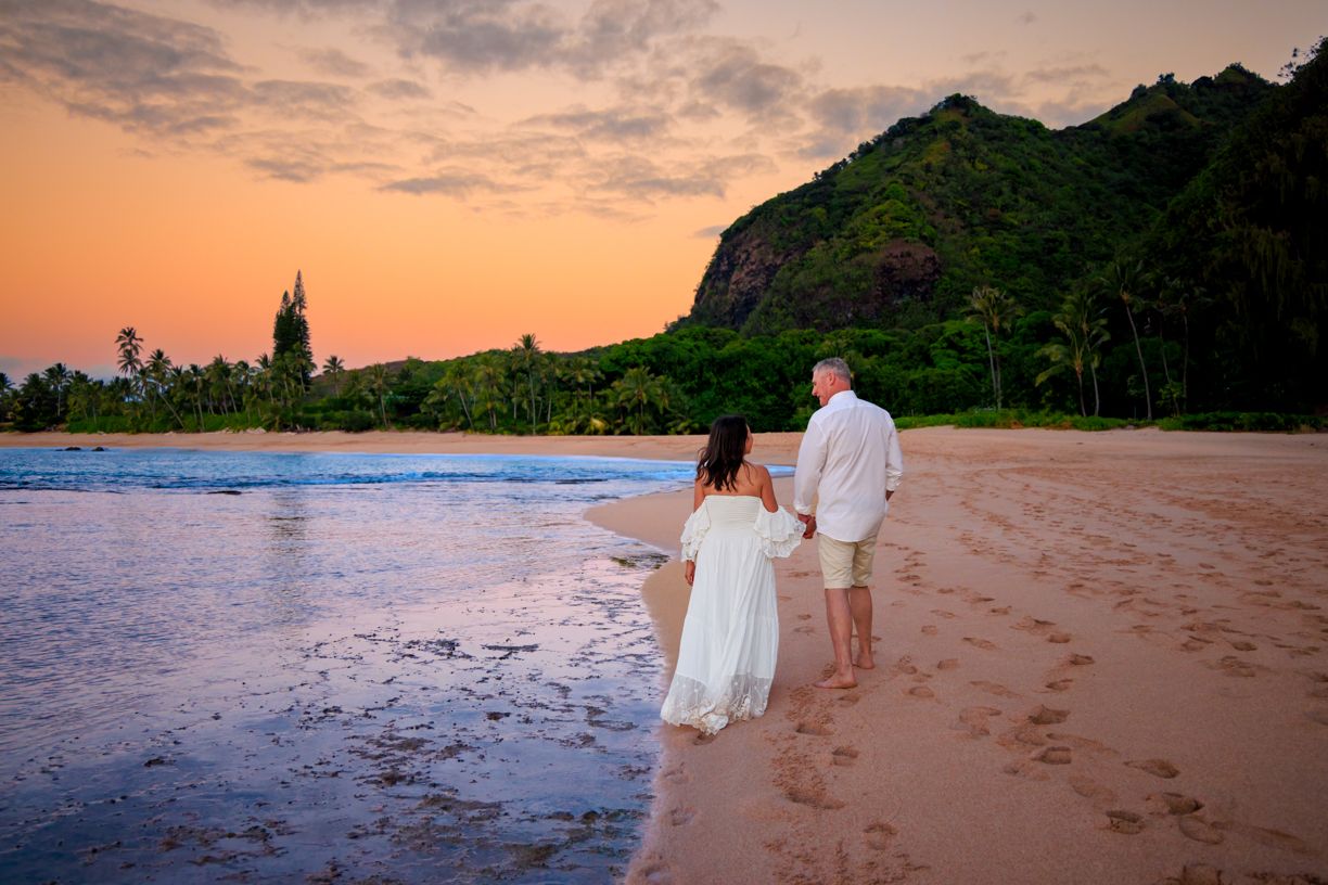 Sunset beach portraits with golden light and mountain silhouettes in the background.