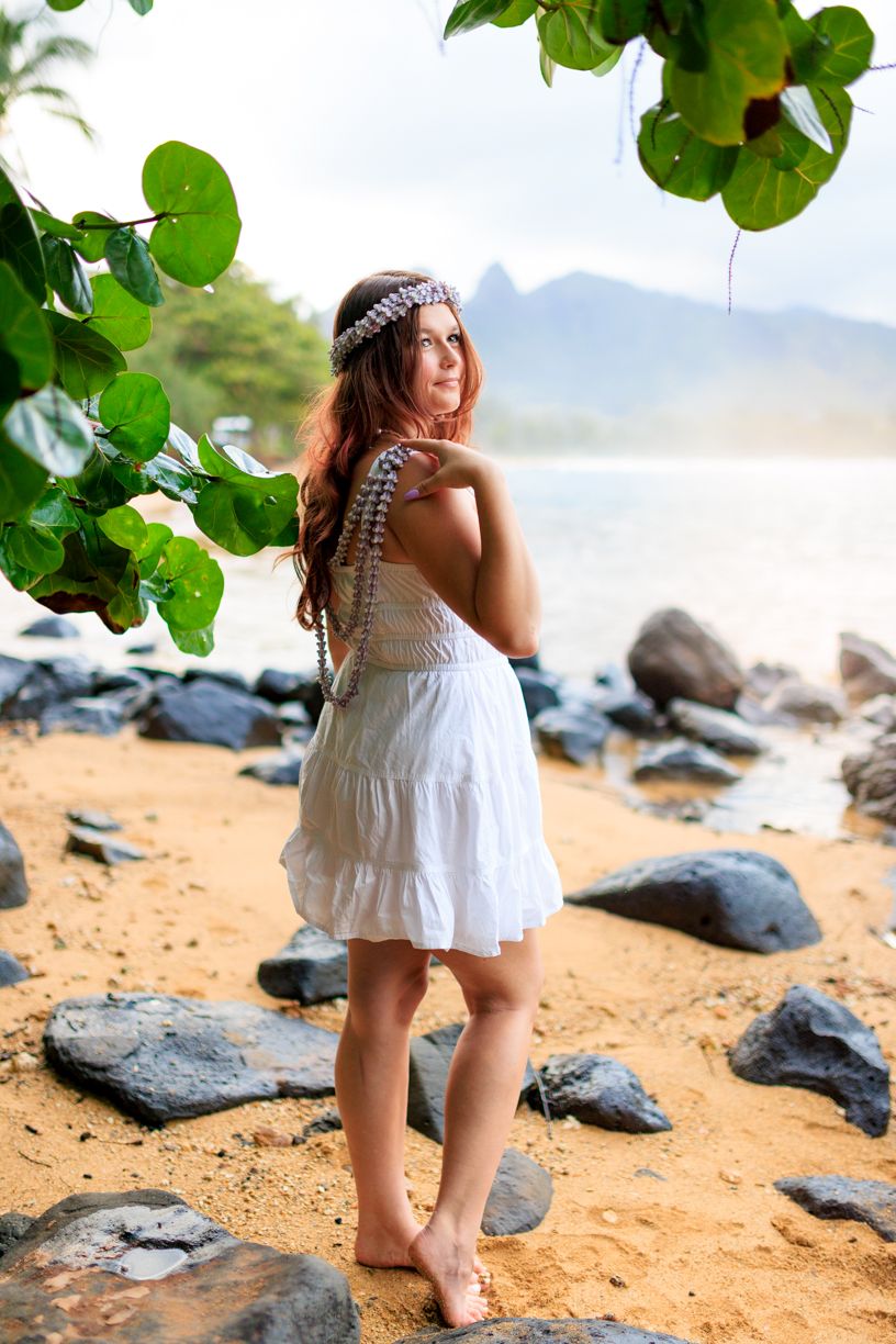 Tropical beach scene with black volcanic rocks and lush green foliage framing the shoreline.